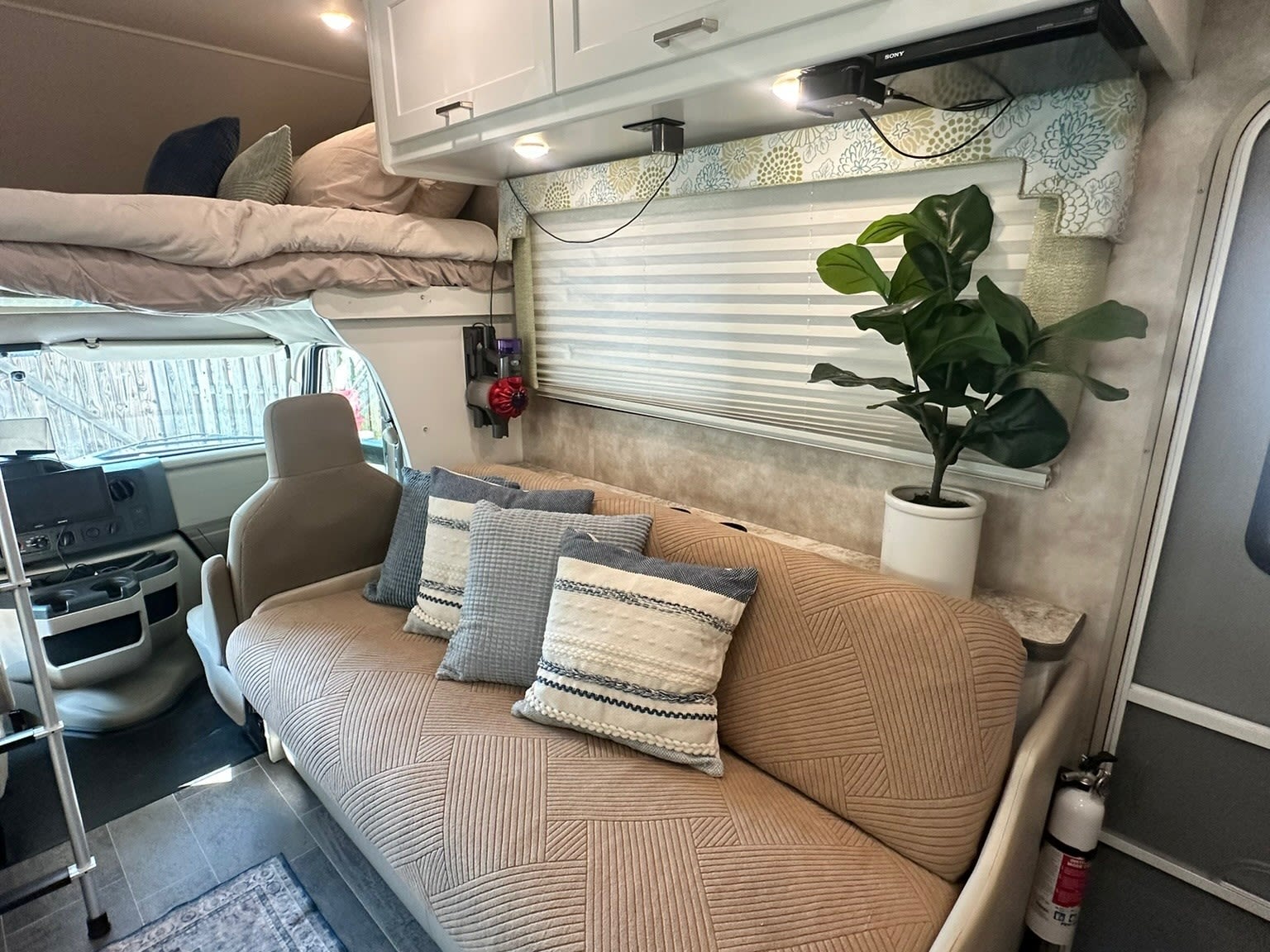 Inside a modern RV rental: a comfy sofa, bunk bed, and plants create a welcoming camper living space for travel.. Winnebago Minnie Winnie 2018