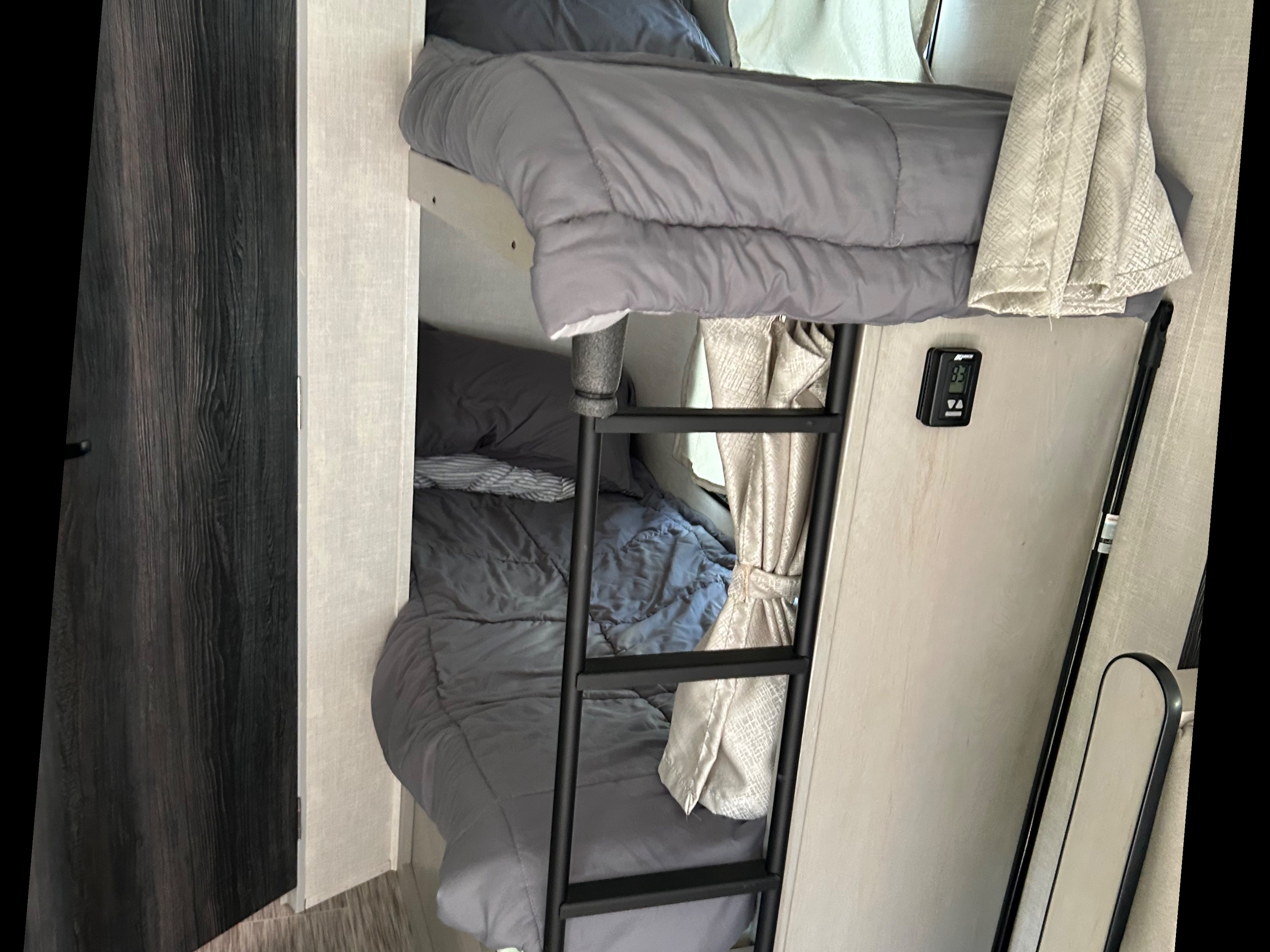 RV rental bunk beds: comfortable sleeping with ladder, gray bedding, and privacy curtains in a cozy interior.. Forest River Ibex 2022