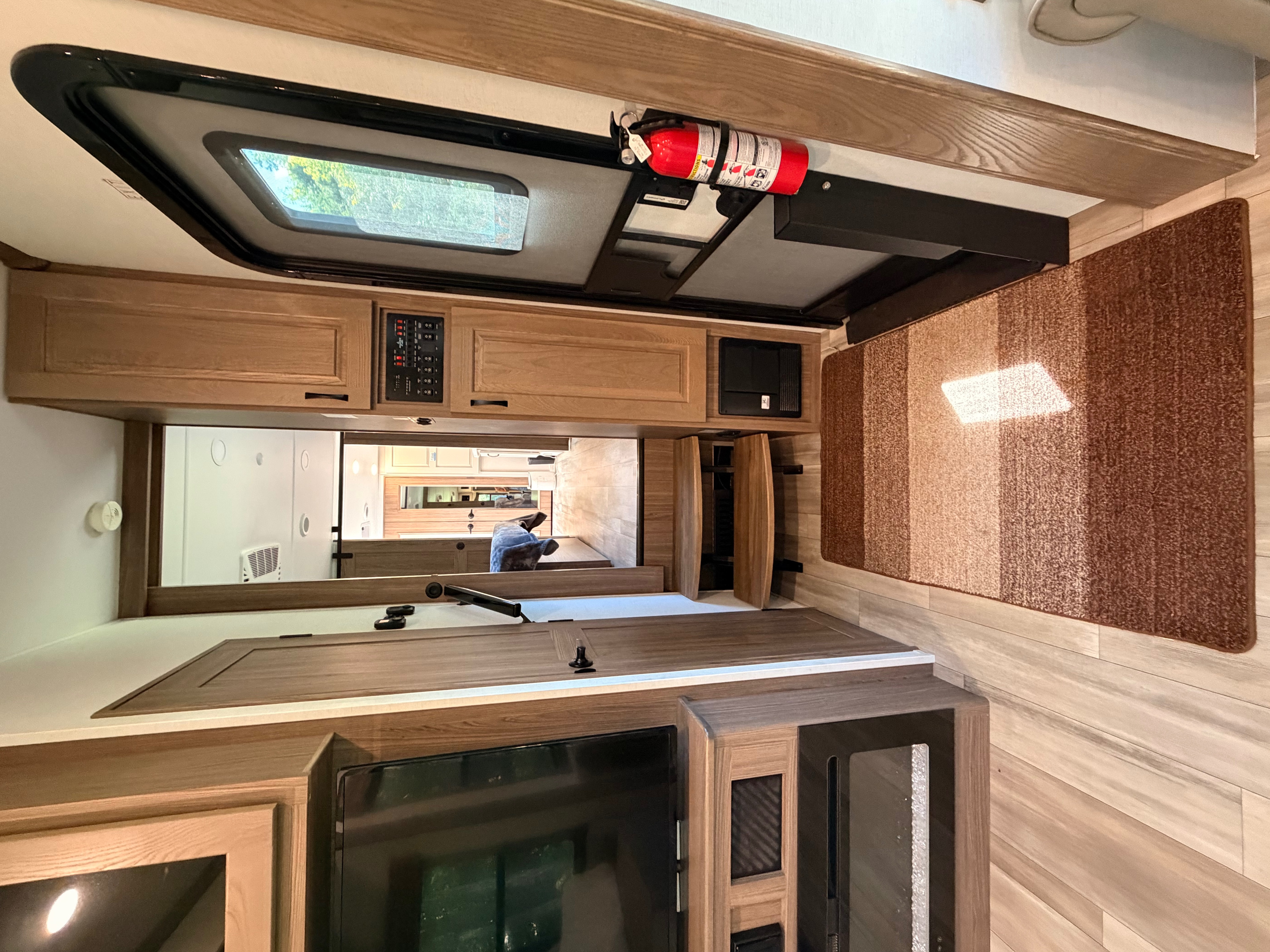 Spacious RV rental interior featuring modern cabinetry, a skylight, TV, and essential safety features like a fire extinguisher.. Alliance RV Paradigm 2024