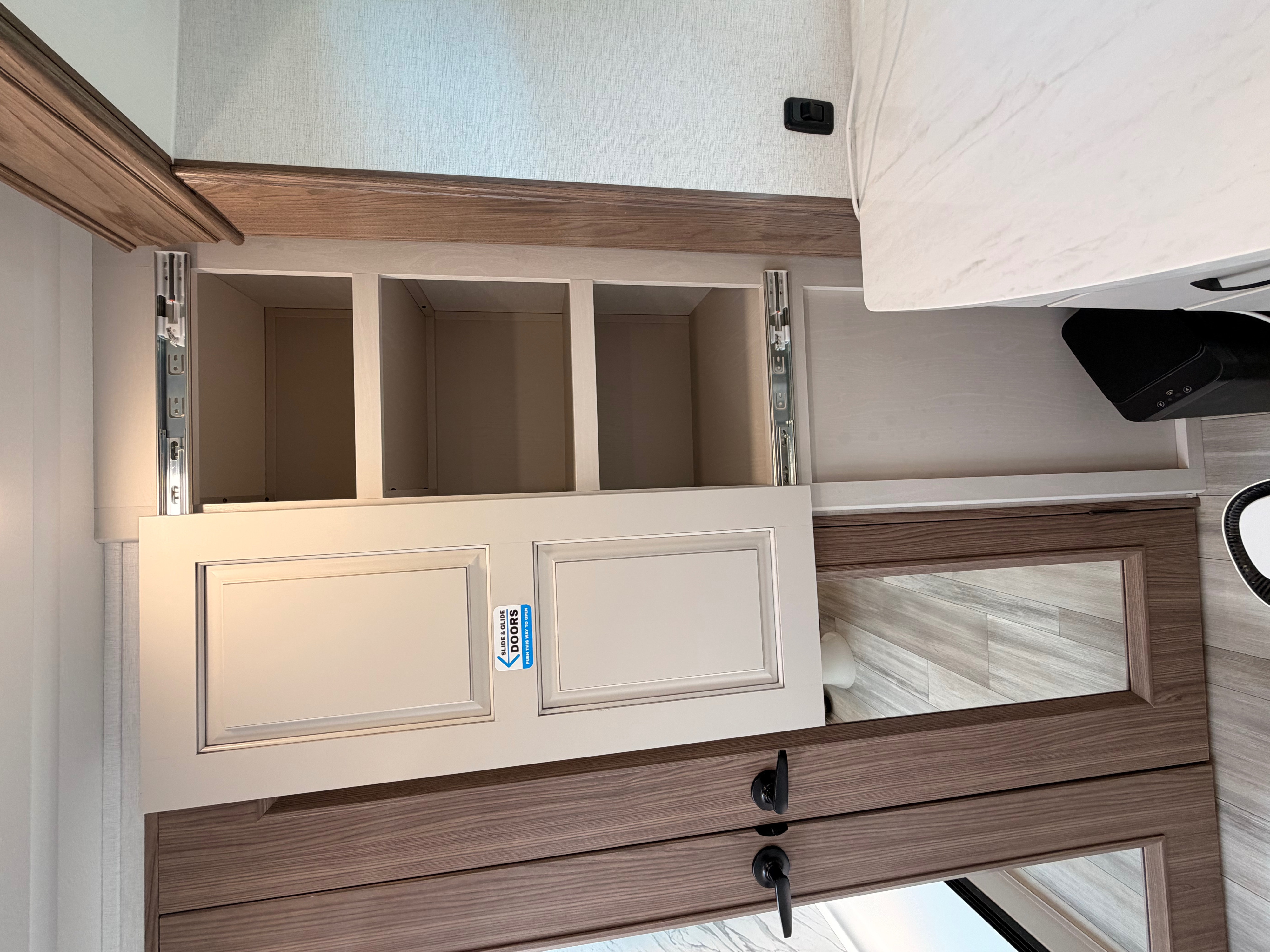 RV rental storage: Open slide & glide cabinet reveals three compartments. Below are mirrored doors. Practical interior design for travel.. Alliance RV Paradigm 2024