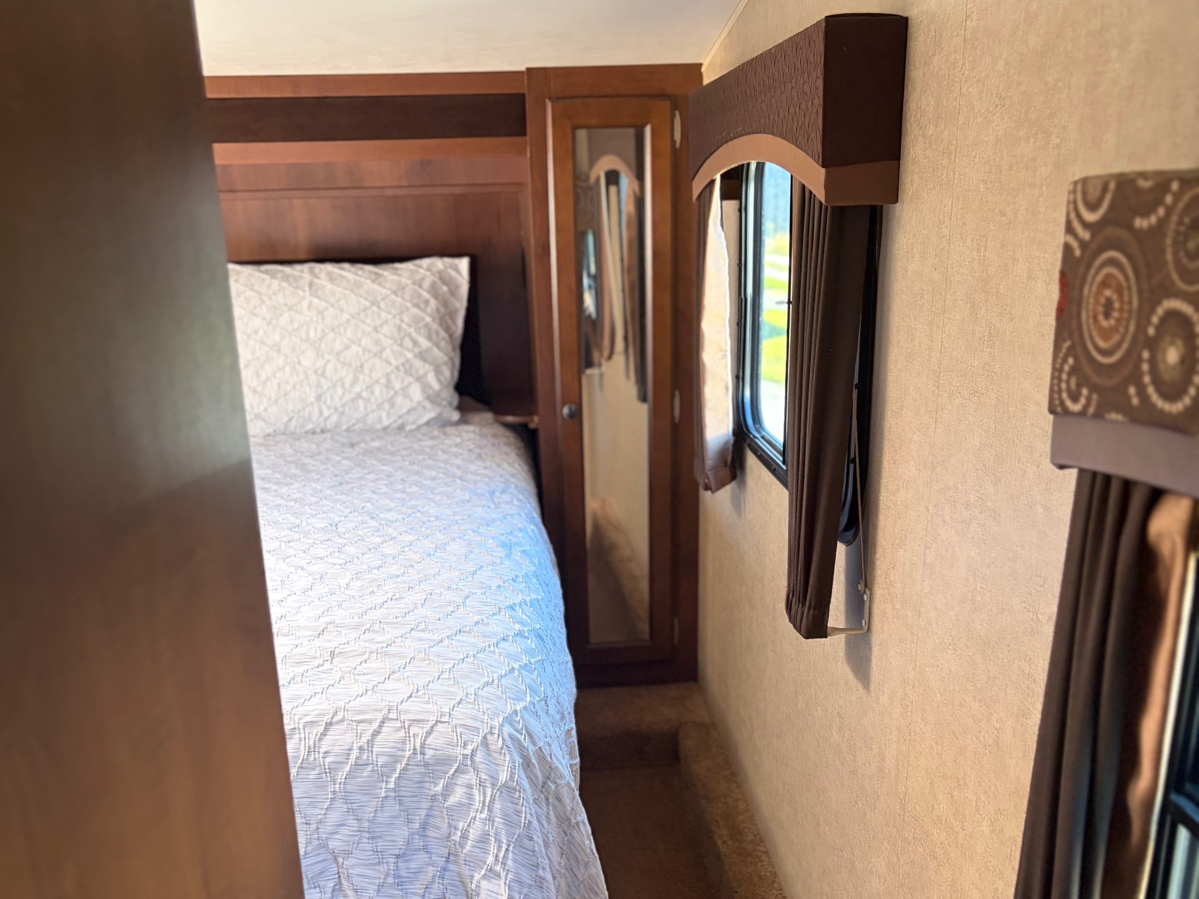 RV rental bedroom: a cozy space with a white bed, mirrored wardrobe, and window with brown curtains. Perfect for travelers.. Jayco Eagle HT 2014