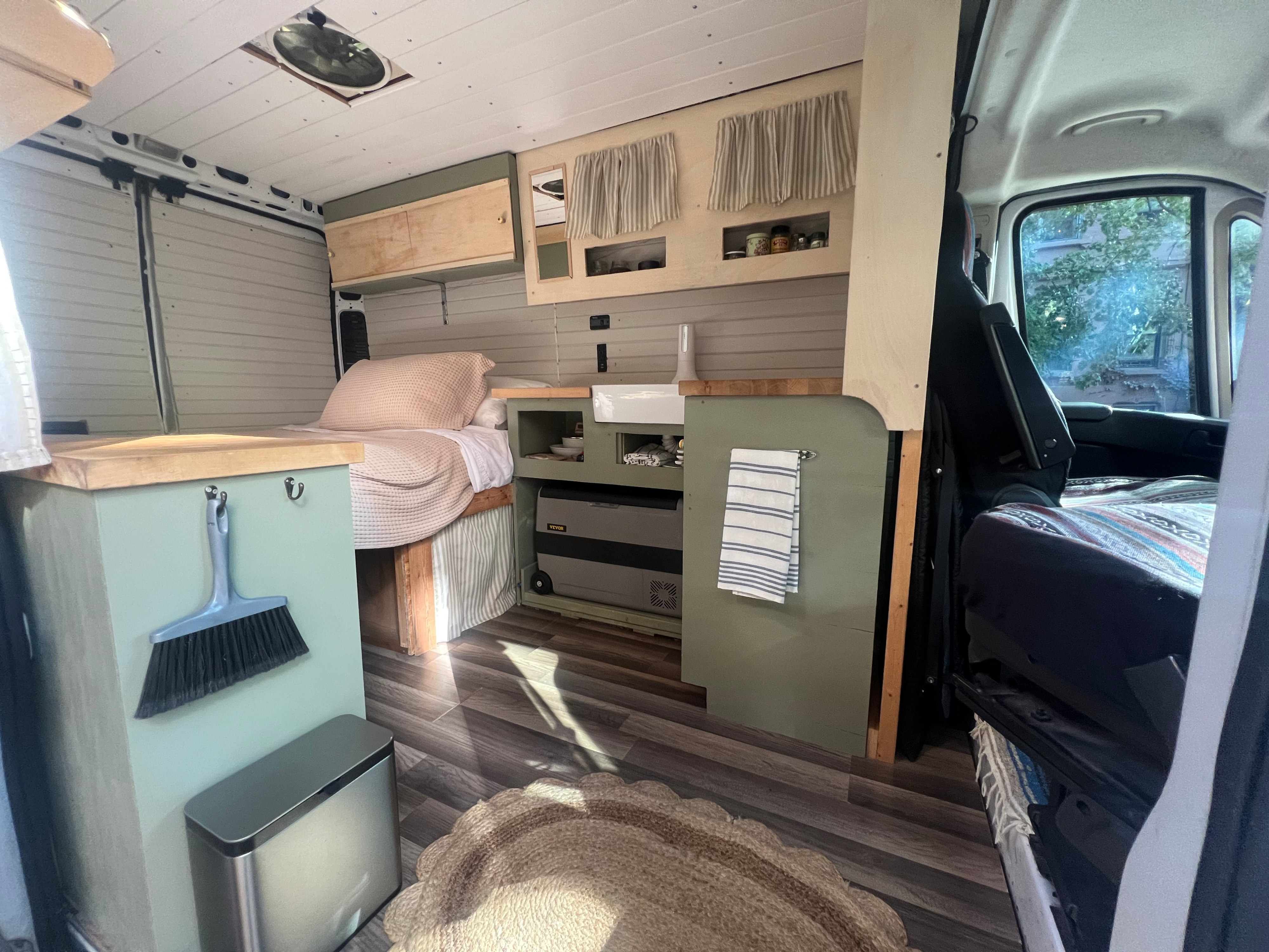 Cozy RV rental interior with bed, kitchenette, and smart storage. Perfect for van life adventures.. Dodge Promaster 2500 high roof 2019