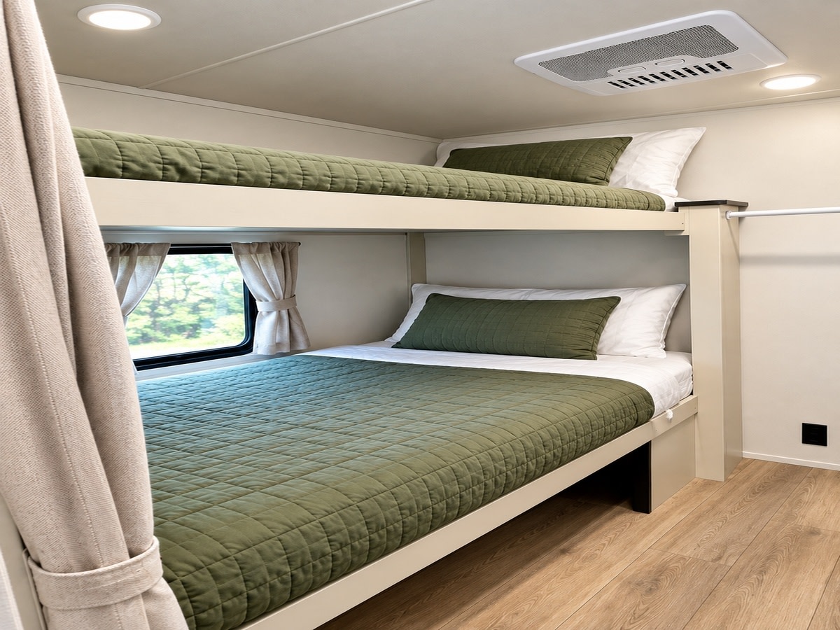 Comfortable bunk beds with green bedding and window views in this cozy RV rental, complete with AC for family travel.. Forester Shasta 2025