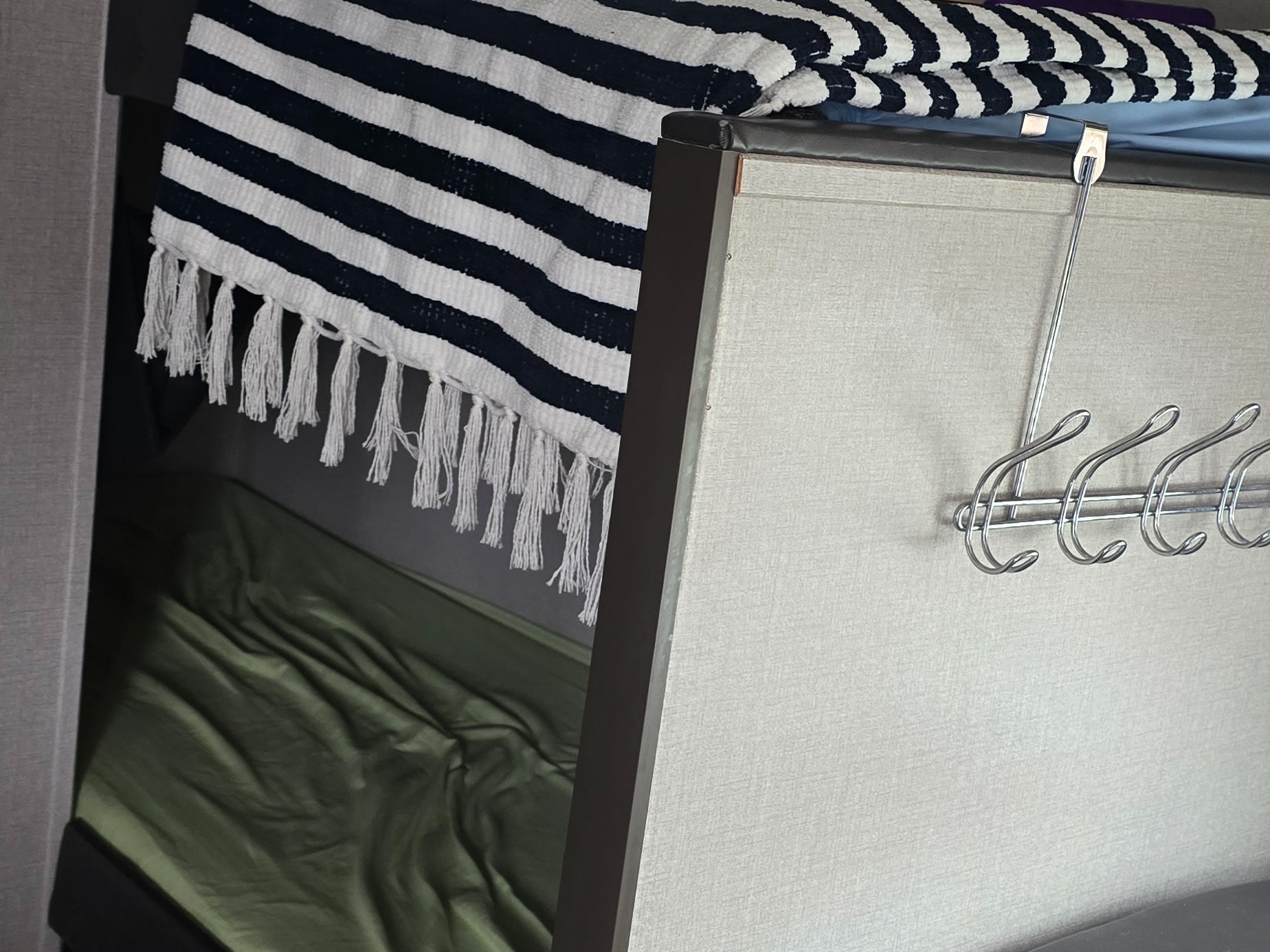 Inside an RV rental: a lower bunk with green sheets, a striped blanket on the upper bunk, and a handy metal hook rack.. Coachmen Catalina 2020