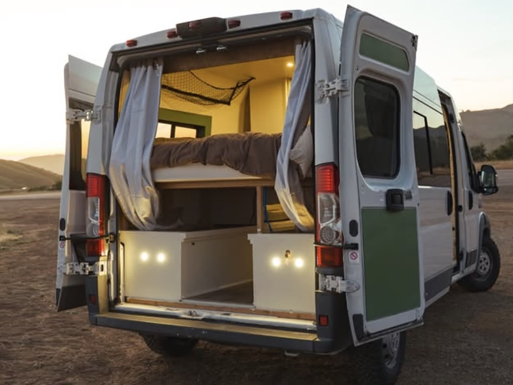 This RV rental camper van opens to a cozy interior with a bed, lit storage, and curtains, ready for adventure.. Dodge Ram ProMaster 2500 2015
