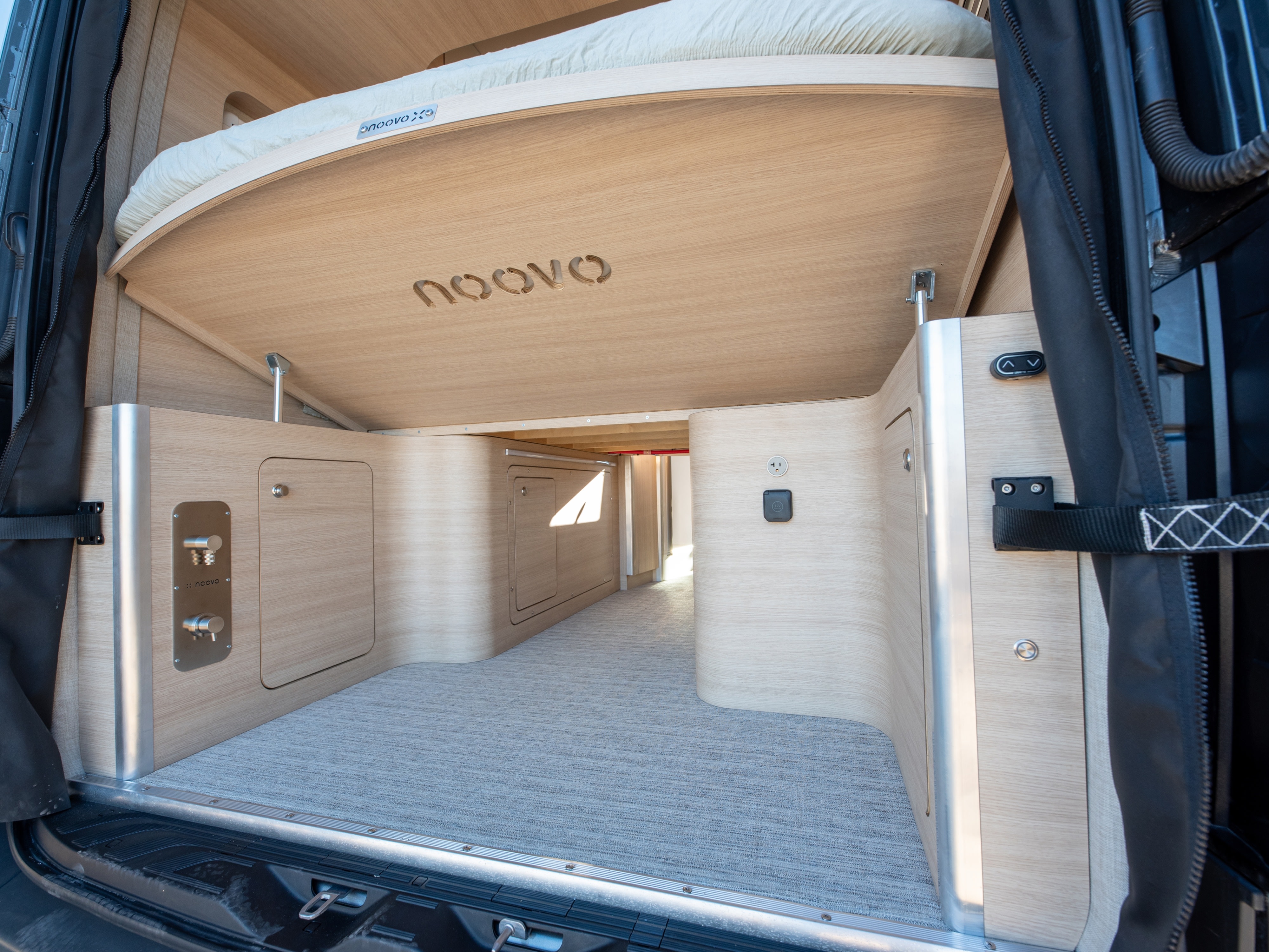 Modern RV rental interior showcasing a liftable bed and spacious under-bed storage, perfect for compact camper van living.. Noovo Noovo Next 2026