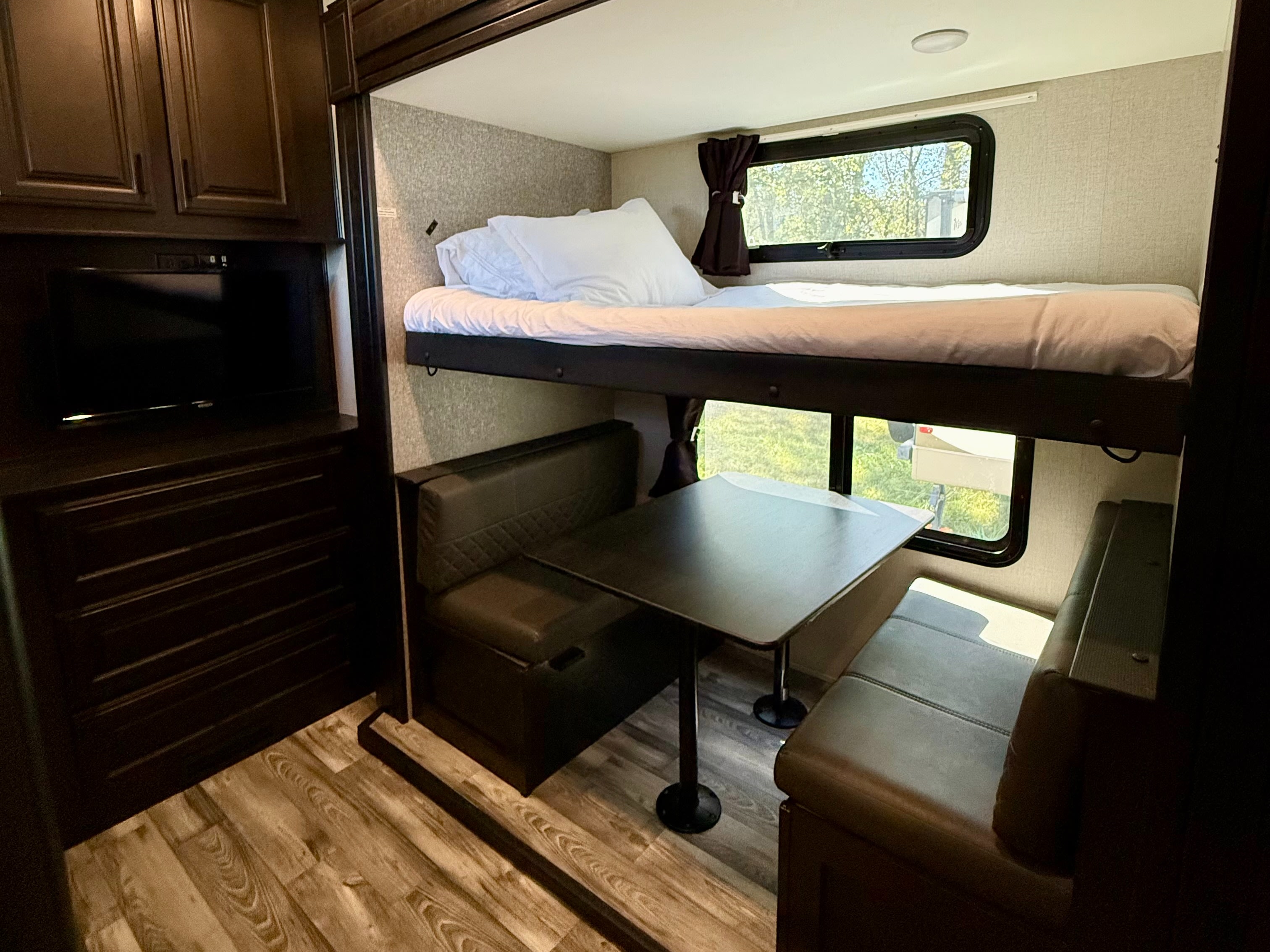 RV rental interior: bunk bed, dinette with table & seating, and a TV entertainment unit for comfortable travel.. Highland Ridge RV Open Range 2022