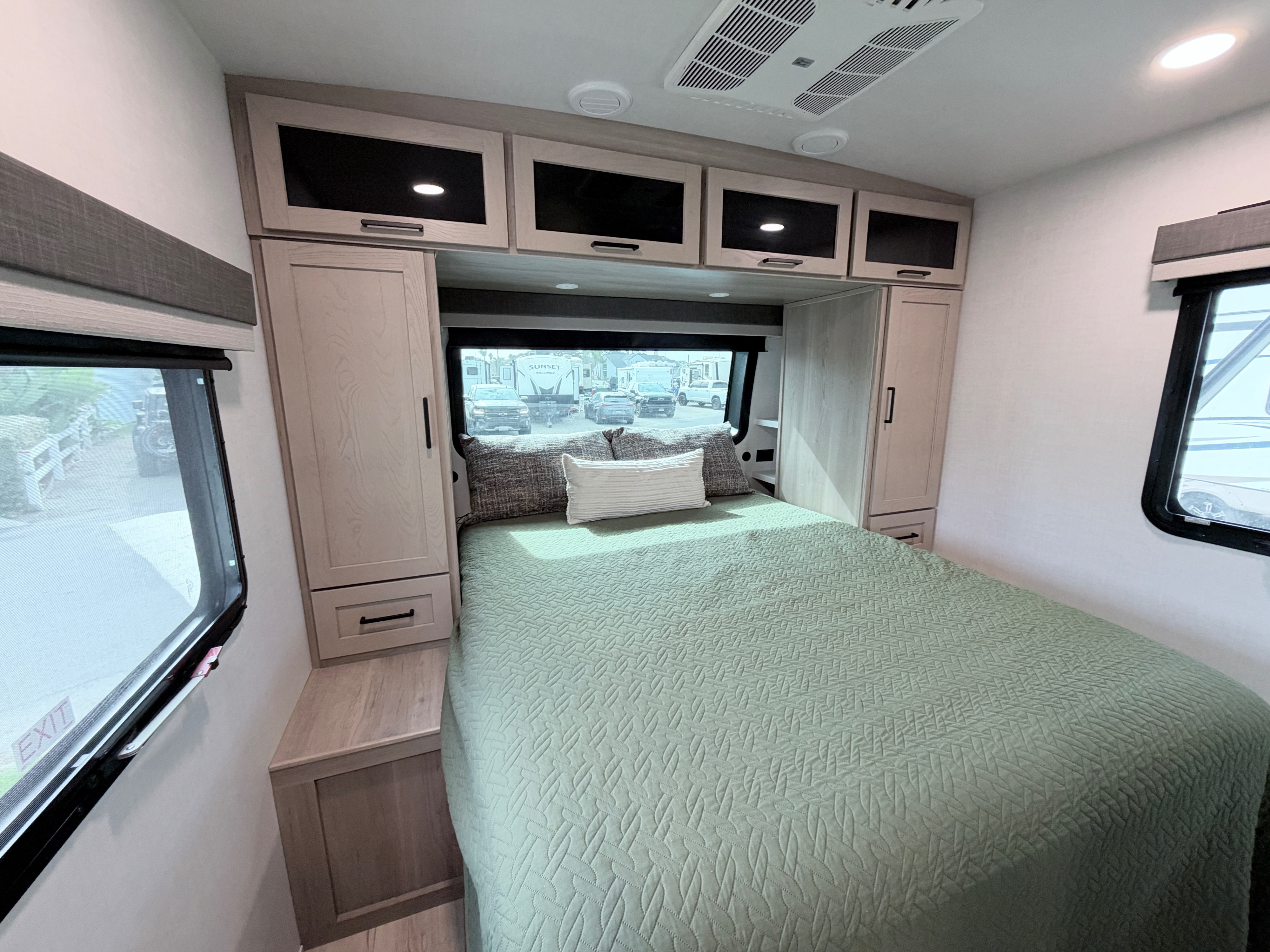 Comfortable modern RV rental bedroom featuring a green bed, overhead storage, and large windows. Your cozy home on wheels.. Forest River 2706BH 2026