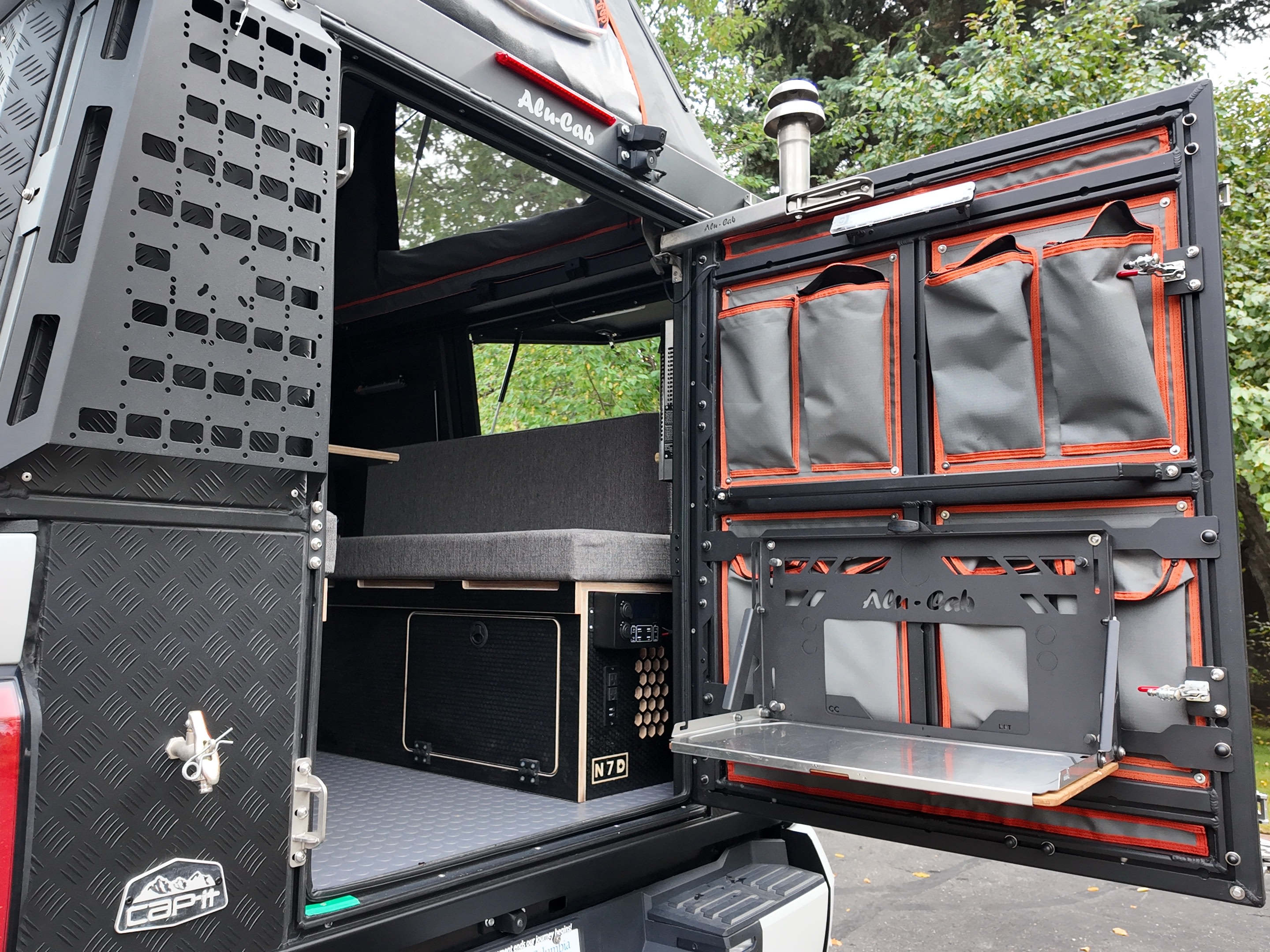 Alu-Cab overland camper interior, ideal for an rv rental. Features modular storage, a fold-down table, and N7D power setup.. Toyota Tundra 2022