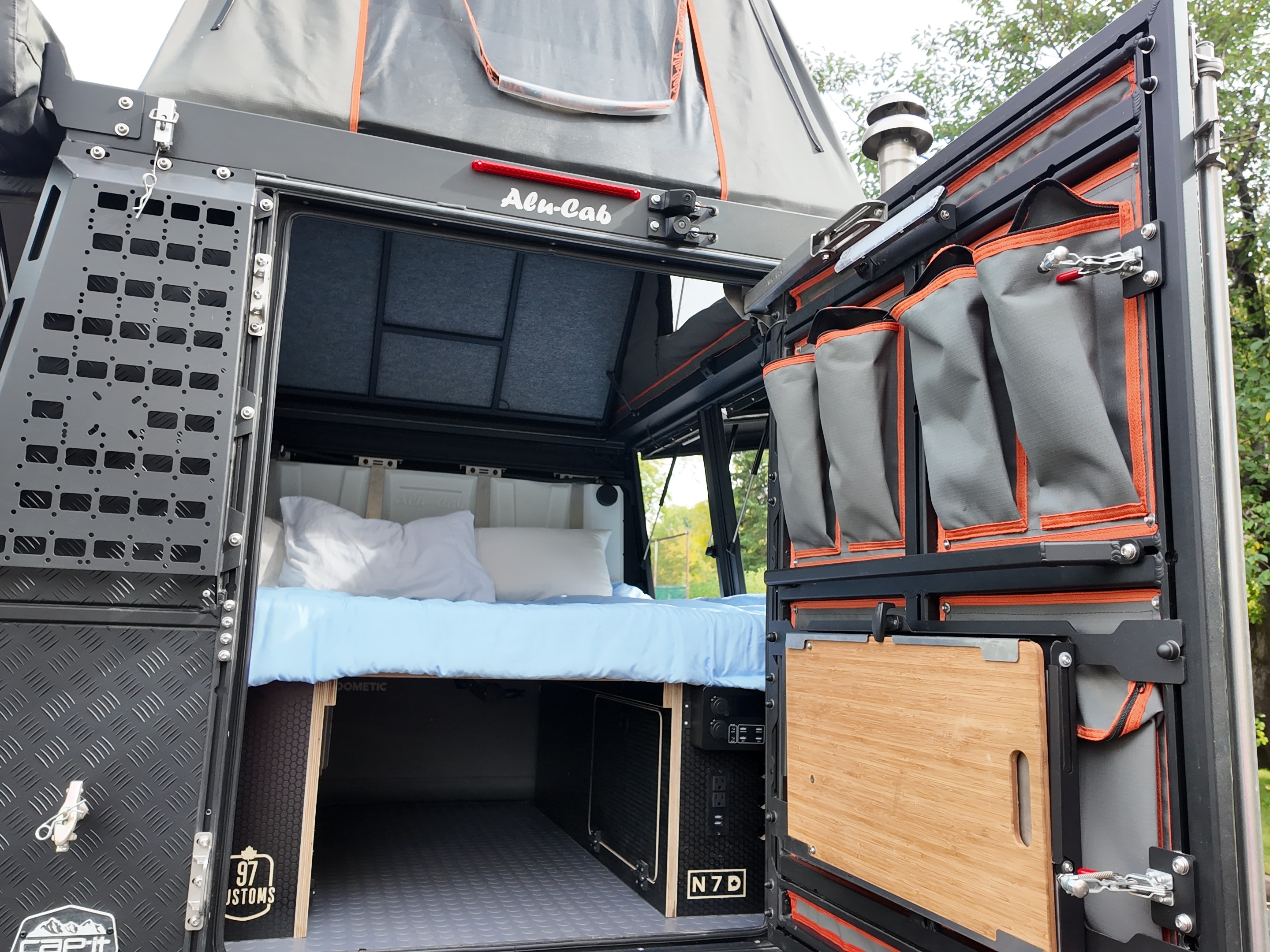 Detailed truck camper rv rental interior reveals a cozy bed, under-bed storage, and clever organized gear on the open rear door.. Toyota Tundra 2022