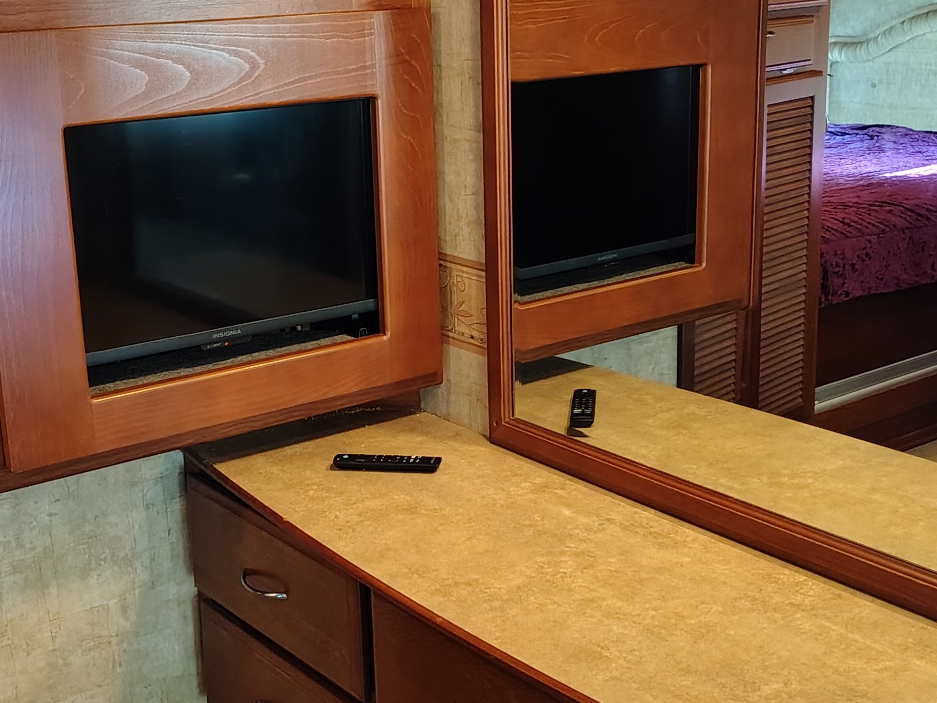 RV rental bedroom interior featuring two TVs, a large mirror, and wood cabinetry with storage for a comfortable stay.. Fleetwood 38v 2008
