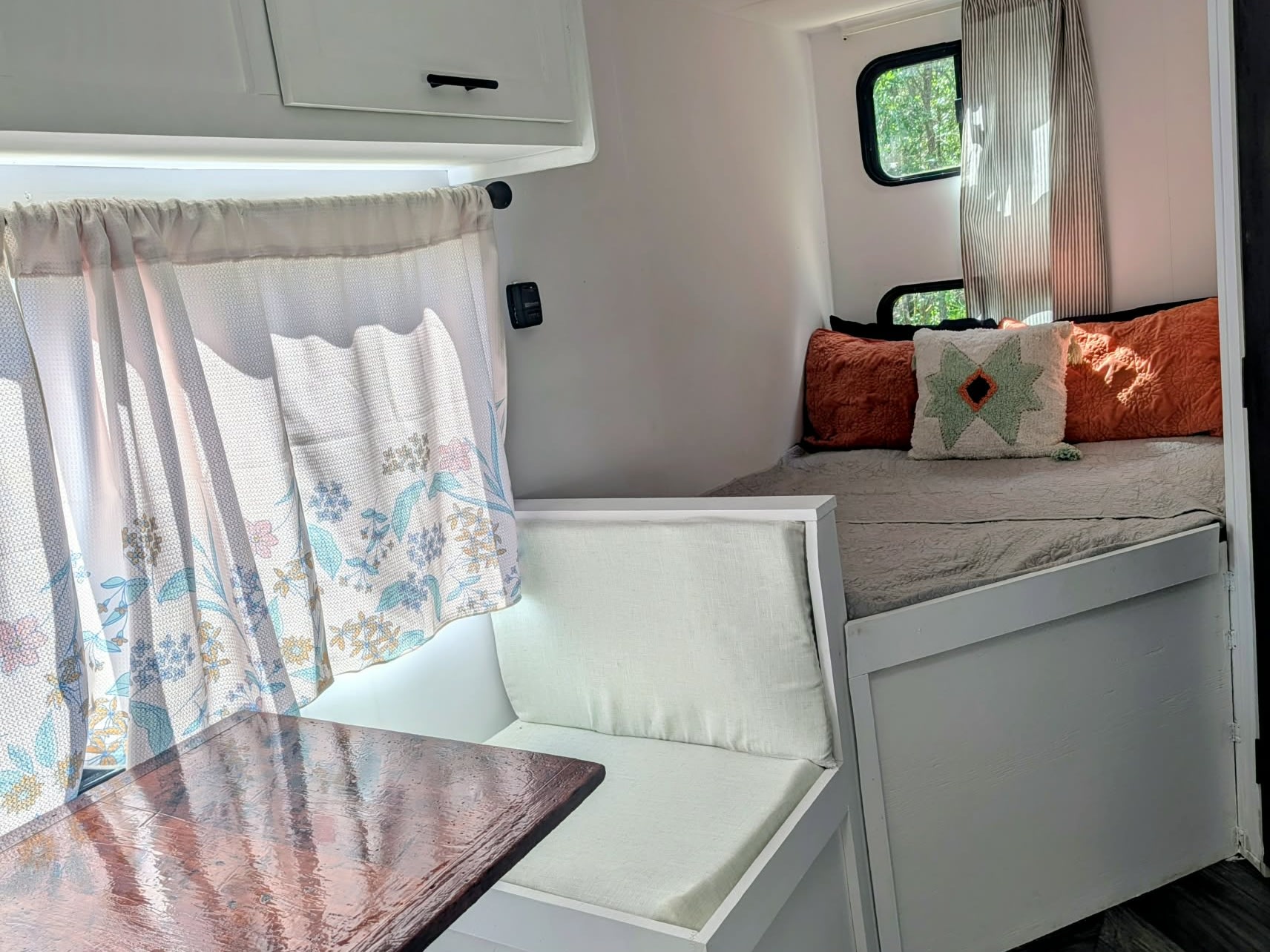 Bright RV rental: a cozy interior with a dinette, floral curtains, and a bed adorned with colorful pillows.. Forest River Salem FSX Plantium 2022