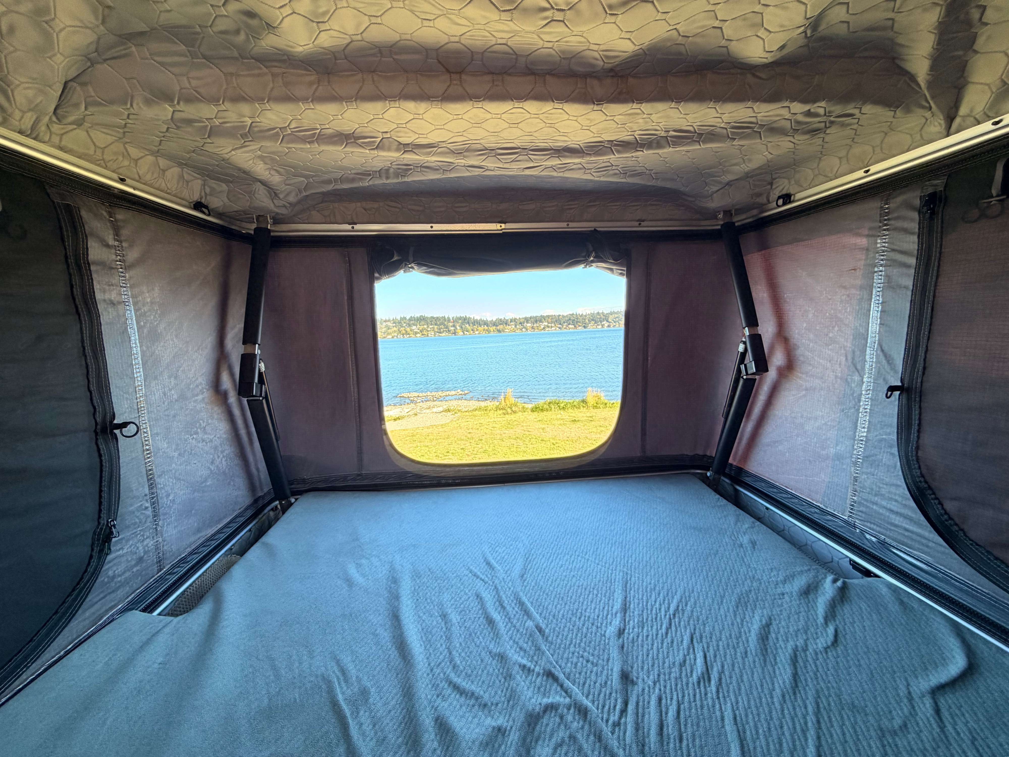 Cozy rooftop tent interior with a scenic lake view, perfect for your next rv rental adventure.. Dodge RAM Promaster 3500 2020