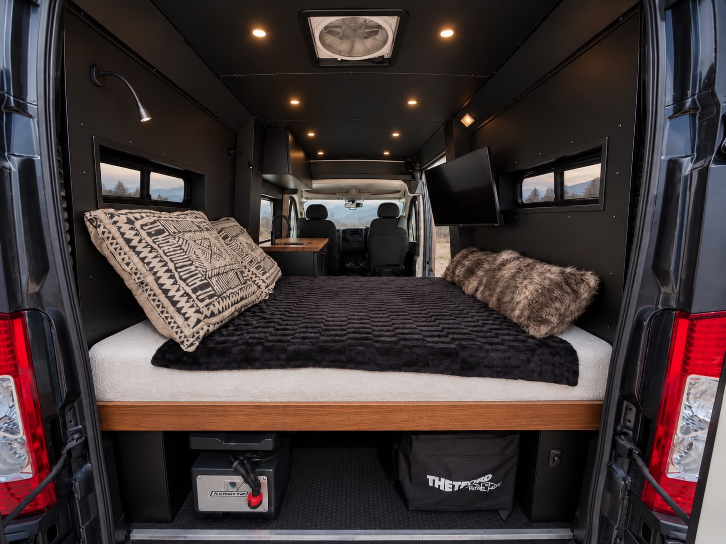 Sleek RV rental interior: large bed, integrated storage (power station, toilet), TV, and windows revealing outdoor scenery.. Dodge Ram 1500 2020