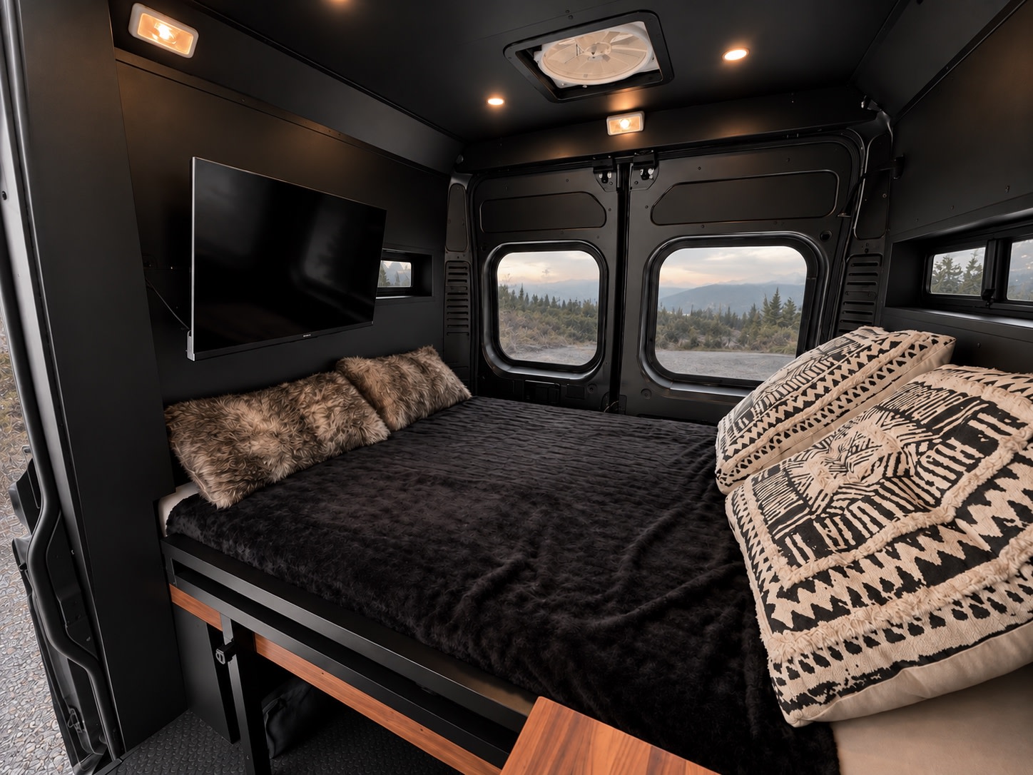 Dark and cozy RV rental bedroom with a plush bed, TV, and scenic mountain views from the windows, perfect for adventure.. Dodge Ram 1500 2020