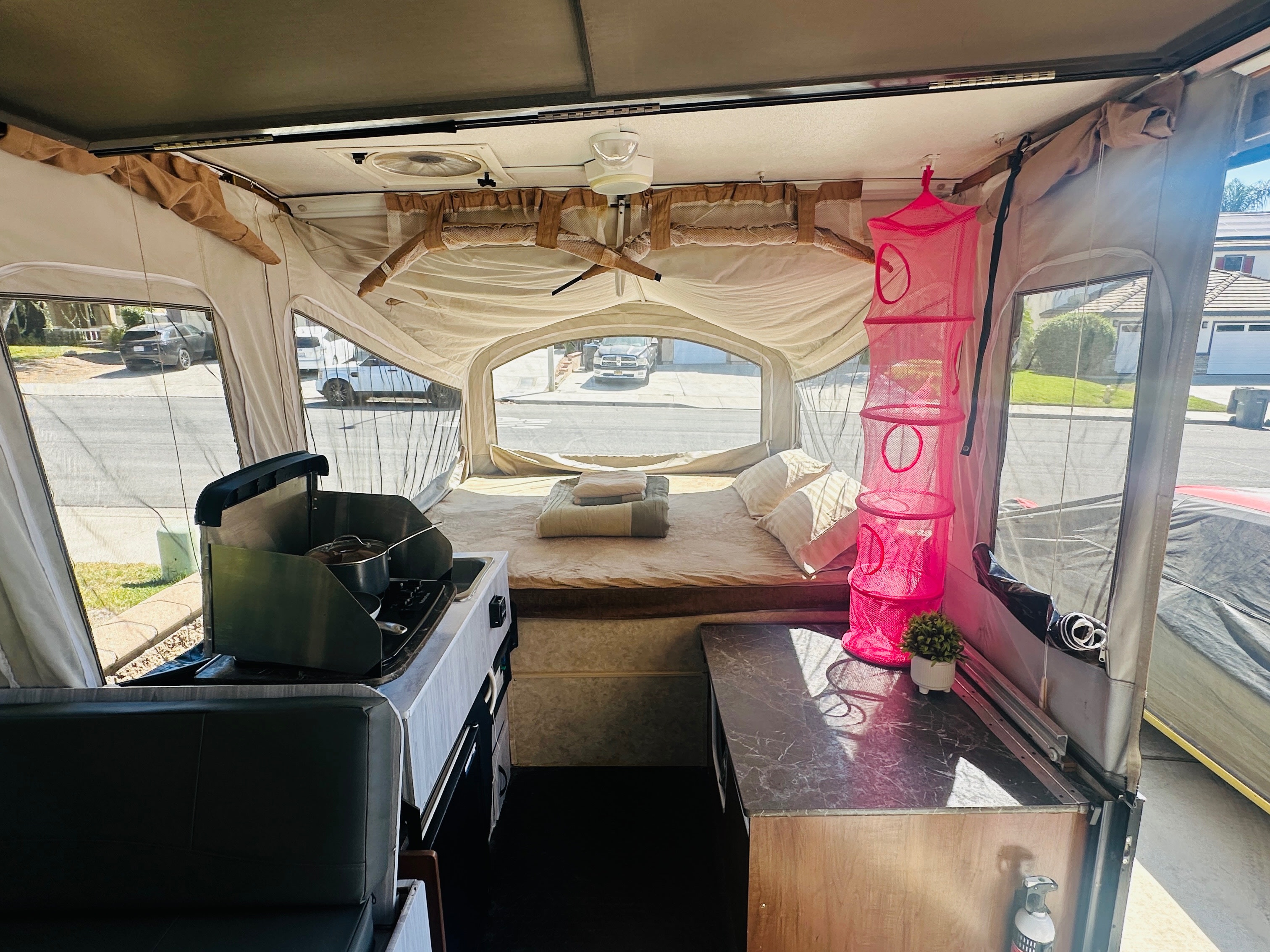 Inside an rv rental pop-up camper: cozy bed, compact kitchen with stove, and living space. Perfect for your next adventure!. Jayco 1209SC 2016