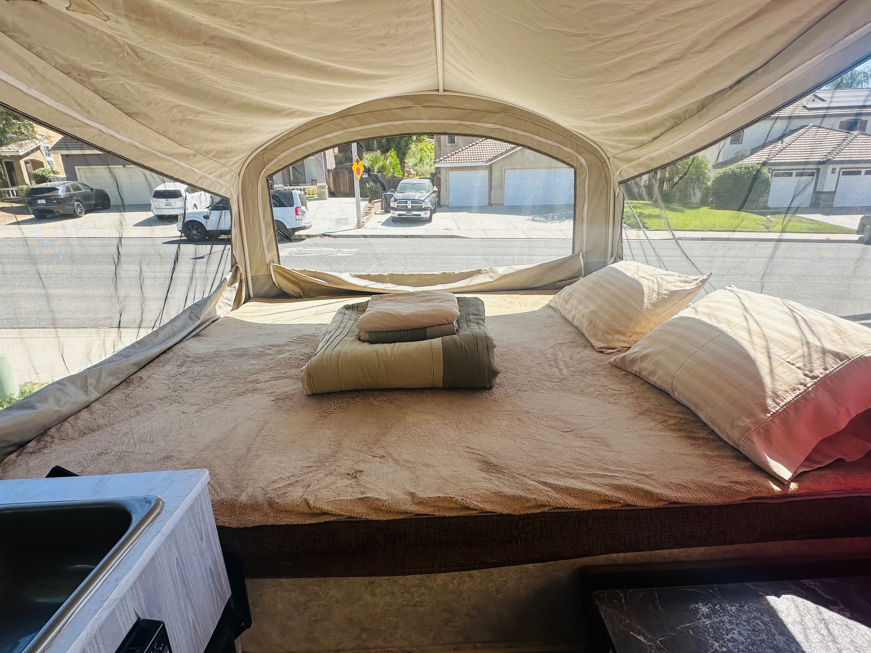 Relax in this RV rental pop-up camper's cozy bed with pillows and blankets. Enjoy street views through the mesh window.. Jayco 1209SC 2016