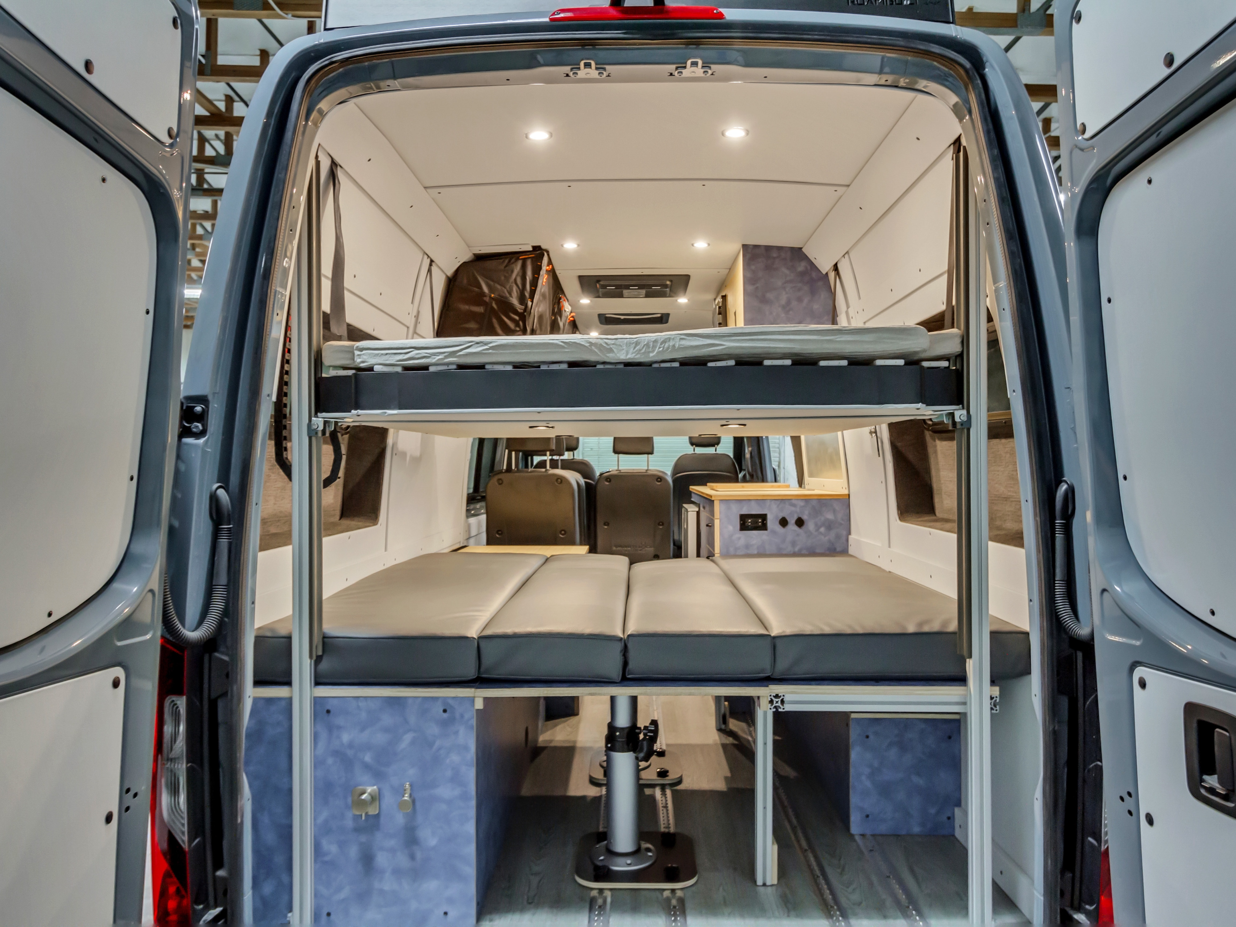 Inside an RV rental: a custom camper van with versatile bunk beds, integrated storage, and modern design.. Mercedes-Benz Sprinter 2025