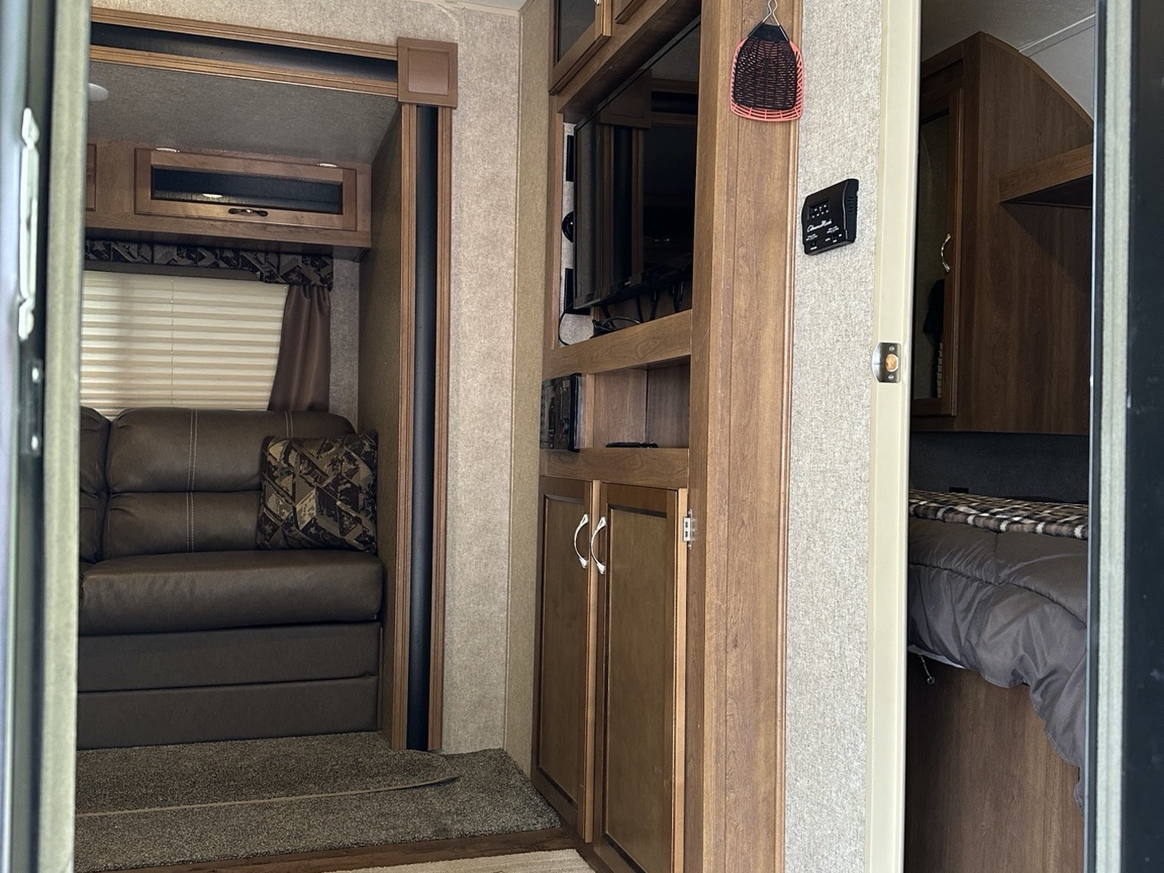 Step inside this cozy RV rental! Features a living area with sofa, entertainment unit, and a peek into the bedroom.. Coachmen Catalina 2017