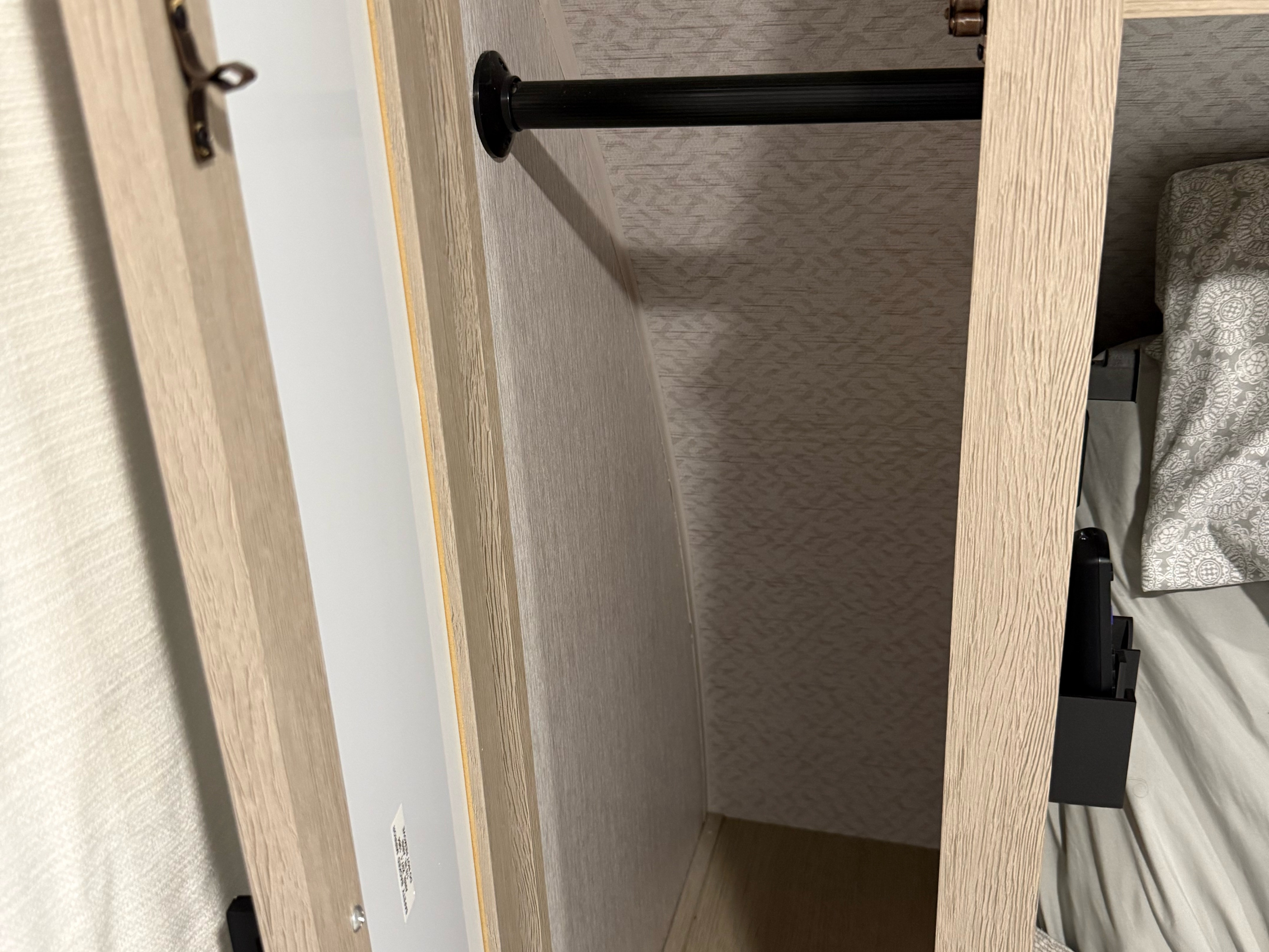 RV rental interior: closet with light wood-grain panels, clothes rod, and patterned walls. Simple storage solution.. Forest River Wildwood X-Lite Platinum 2024