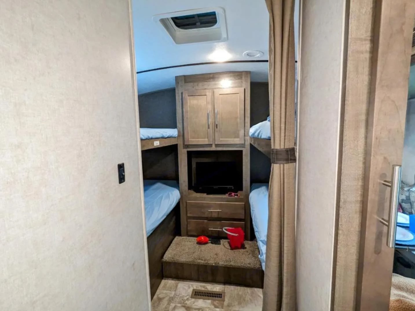 RV rental bunk room with bunk beds, blue sheets, a built-in TV, and wood storage cabinets, perfect for travel.. Forest River Surveyor 2017
