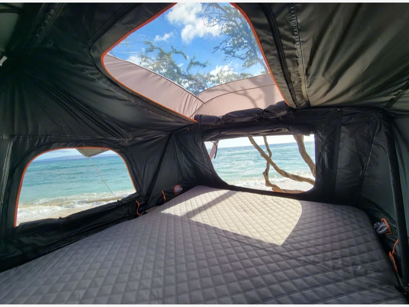Inside a comfy rooftop tent with a quilted mattress, overlooking a serene beach. Ideal for your next rv rental adventure.. Toyota 4Runner Premium 2020