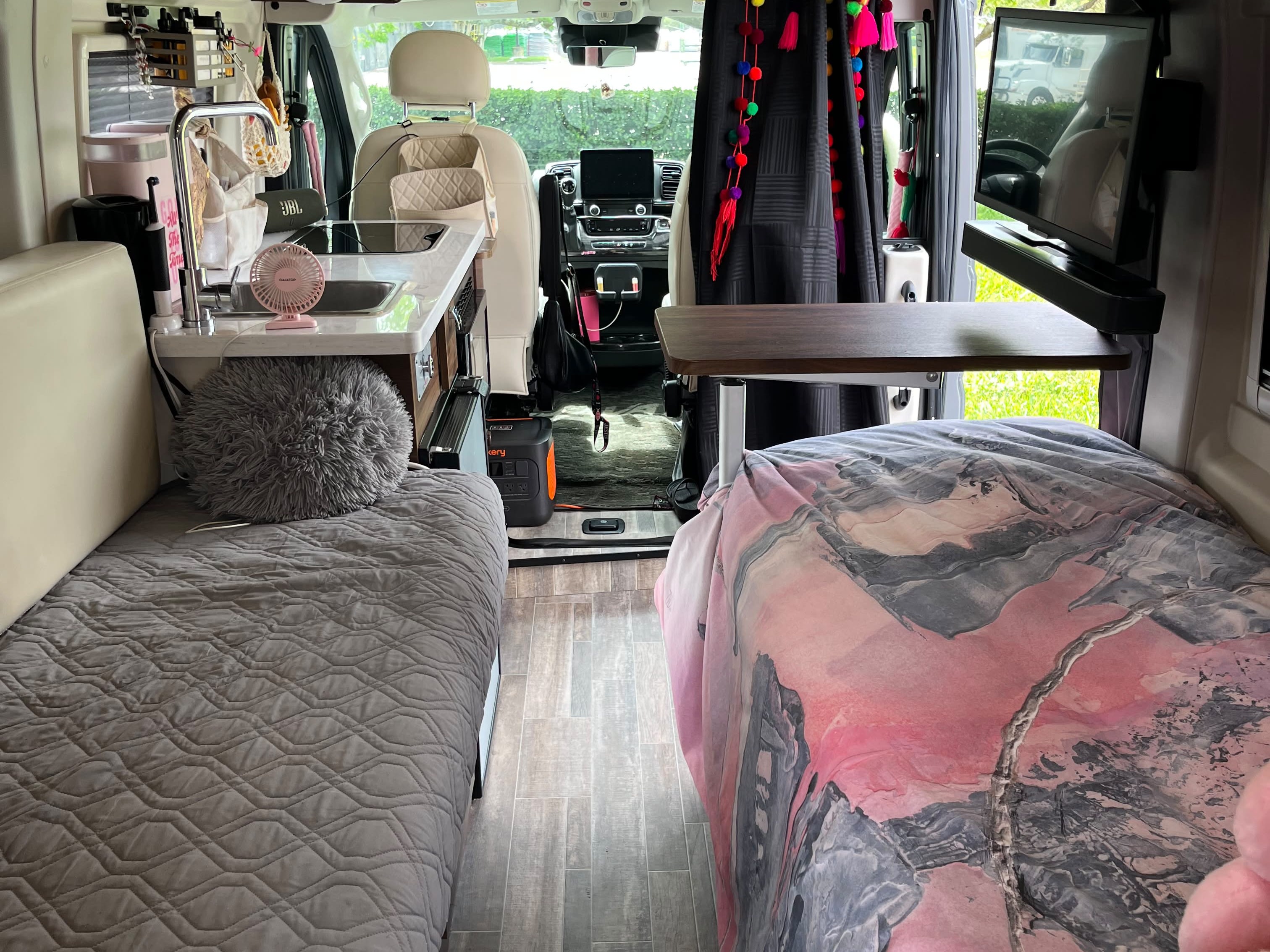 Cozy RV rental interior: view of two beds, a compact kitchen, table, and driver's area, ideal for road trips.. Winnebago Travato 2024