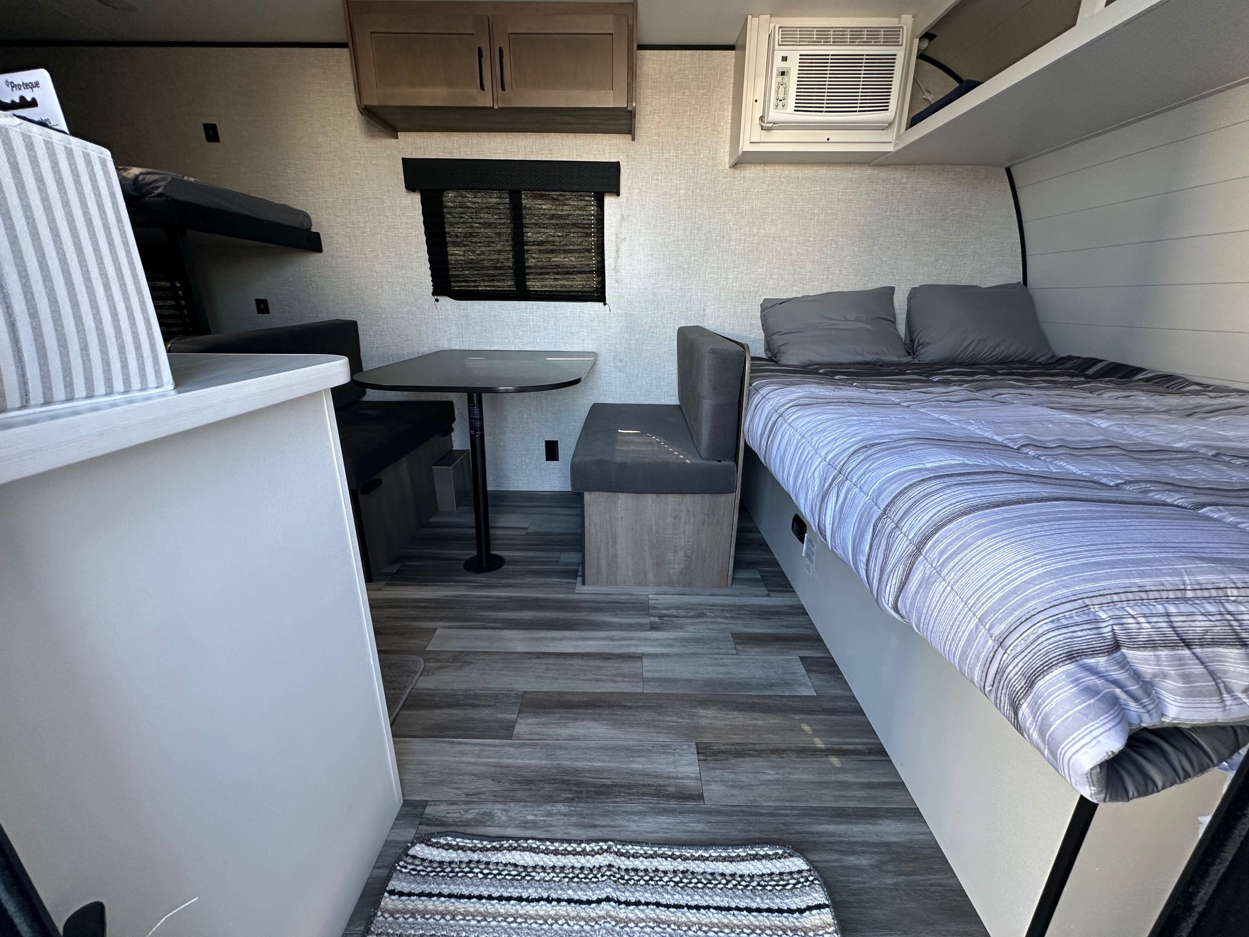 Interior view of a modern RV rental, featuring bunk beds, a dinette, a comfortable main bed, and an AC unit for a cozy travel experience.. Jayco Jay Flight 2025