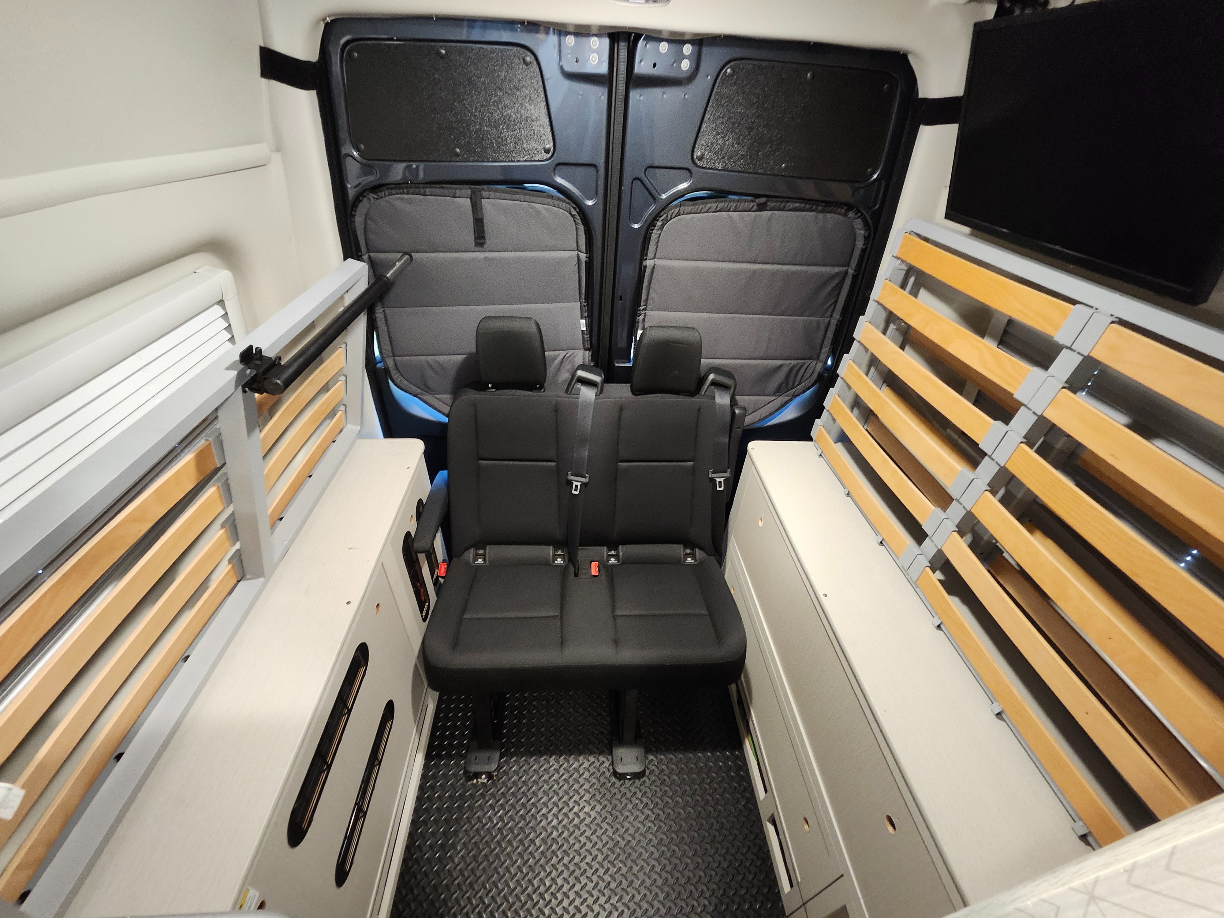 RV rental interior: two passenger seats, clever storage, and adaptable slatted bed frames for compact living.. Mercedes-Benz Sprinter RV Motorhome Campervan 2025