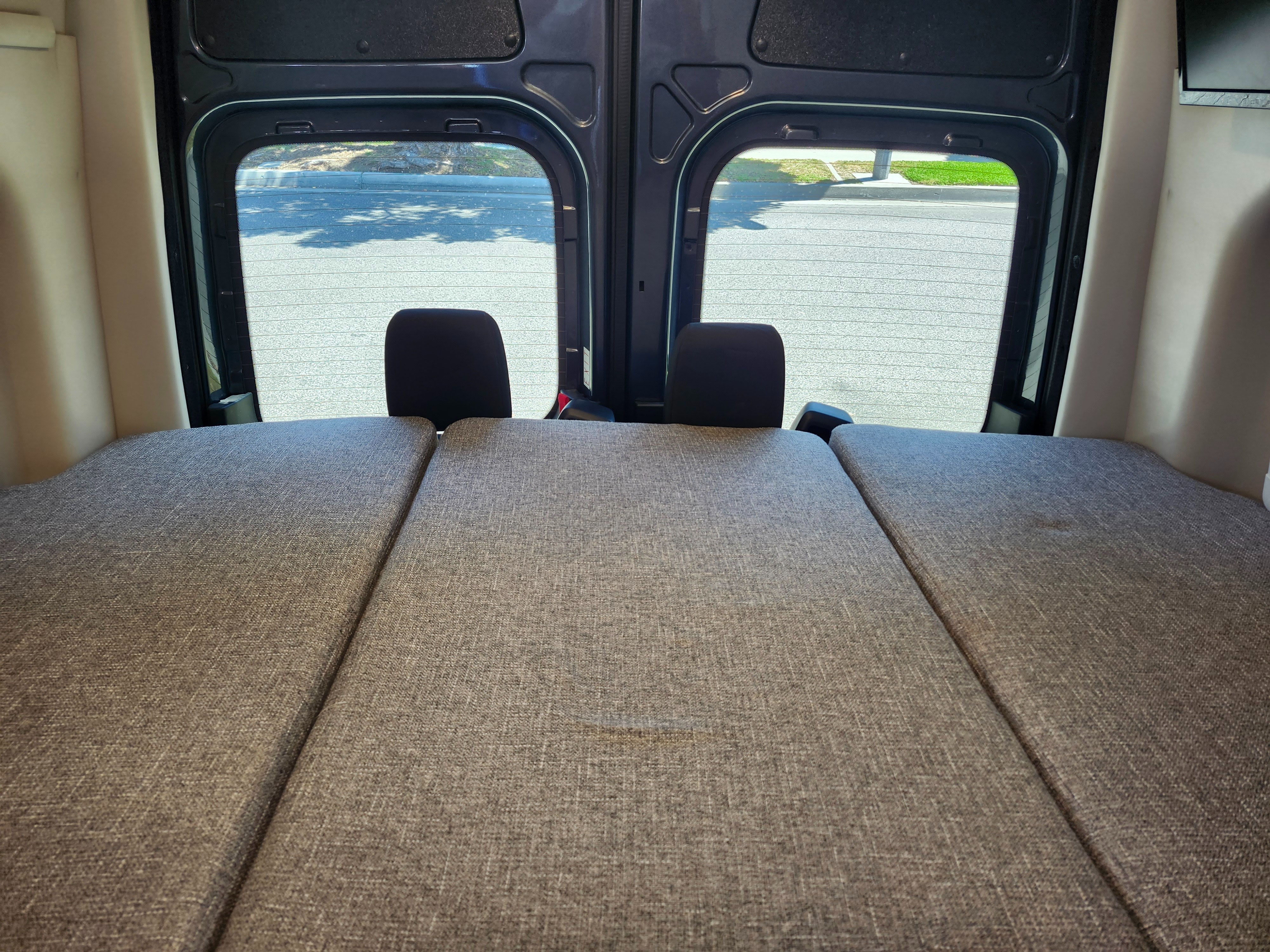Cozy rv rental camper van interior featuring a modular bed setup looking out the rear windows to an outdoor view.. Mercedes-Benz Sprinter RV Motorhome Campervan 2025
