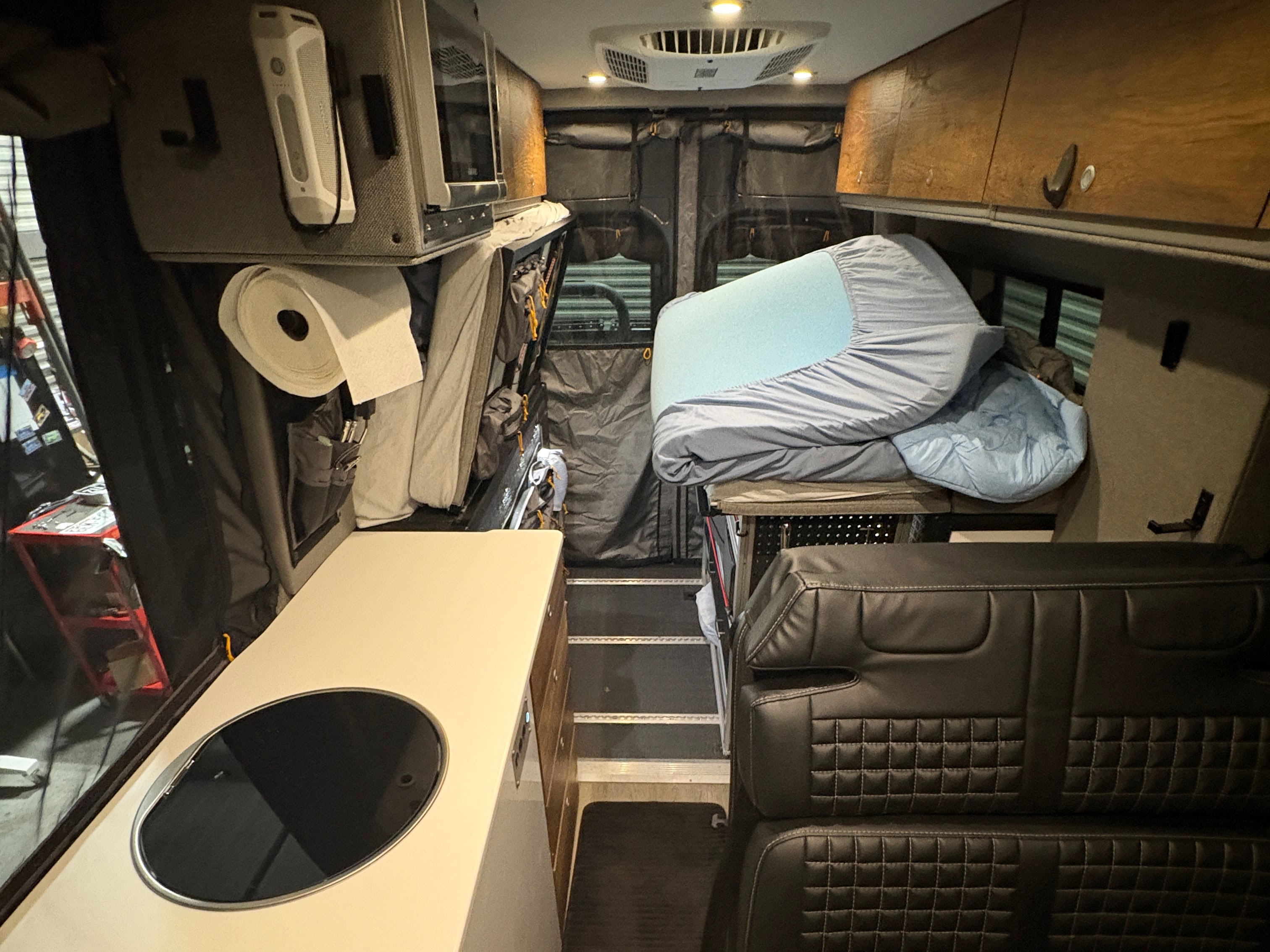 Explore this RV rental's cozy interior, featuring a compact kitchen, comfortable bed, and ample storage for your adventures.. Storyteller Overland Storyteller Overland Class B 2024