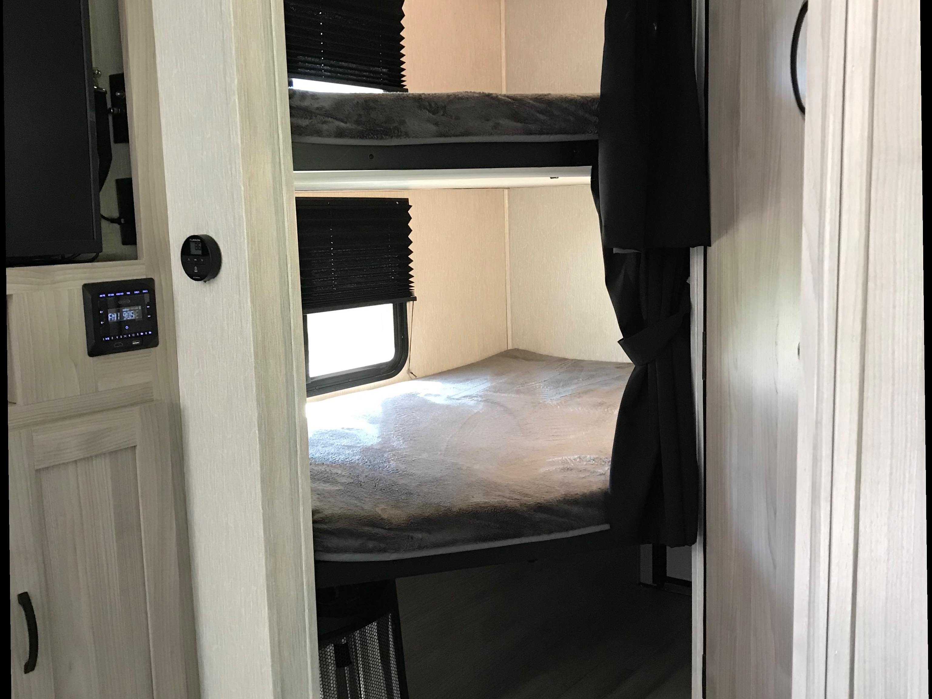Interior of an RV rental showcasing bunk beds, windows with blinds, and a digital climate control panel.. Forest River Coachmen Northern Spirit Ultra Lite 2022
