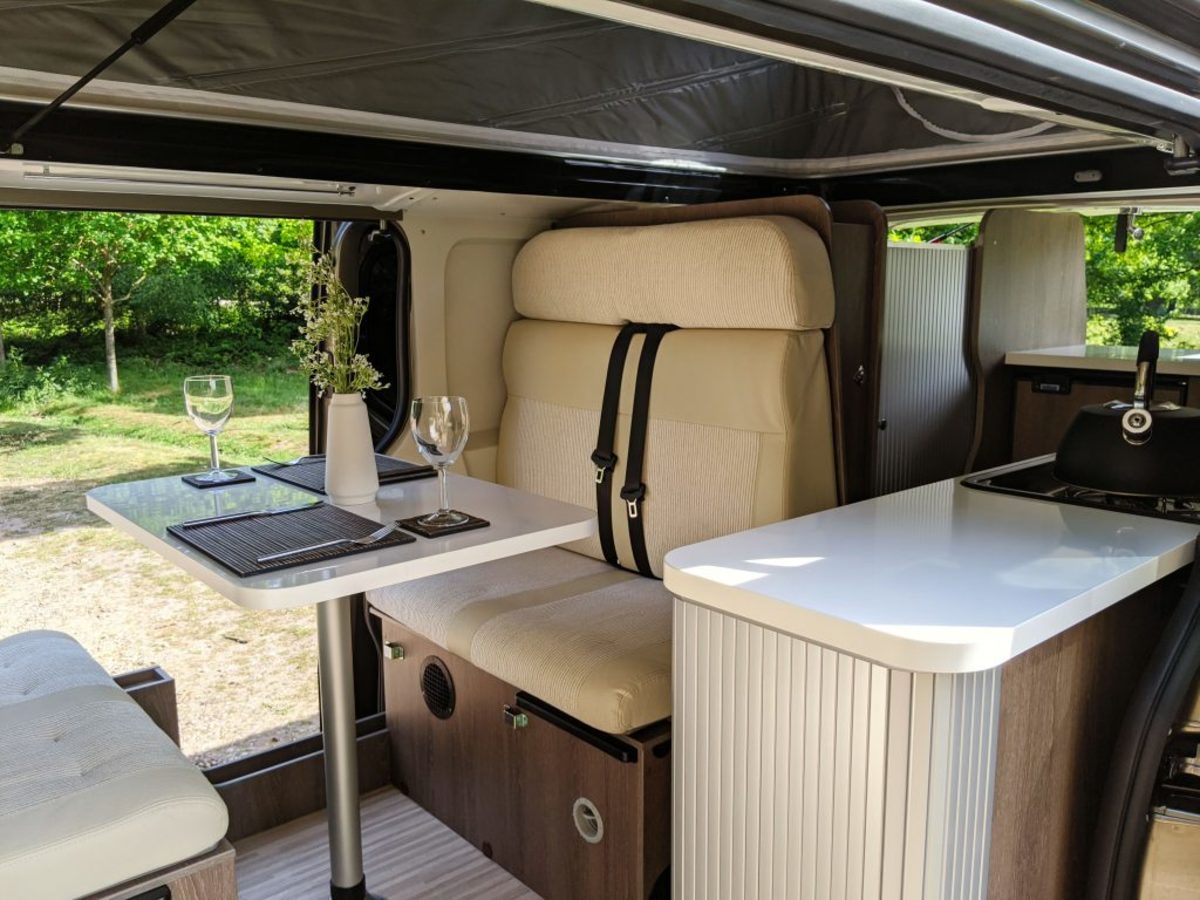 Stylish interior dining for 4 and folding down to a bed for 2. Rudy has 4 belted seats - 2 up front and 2 at the back. The bathroom is behind the seats, with a wardrobe in between.