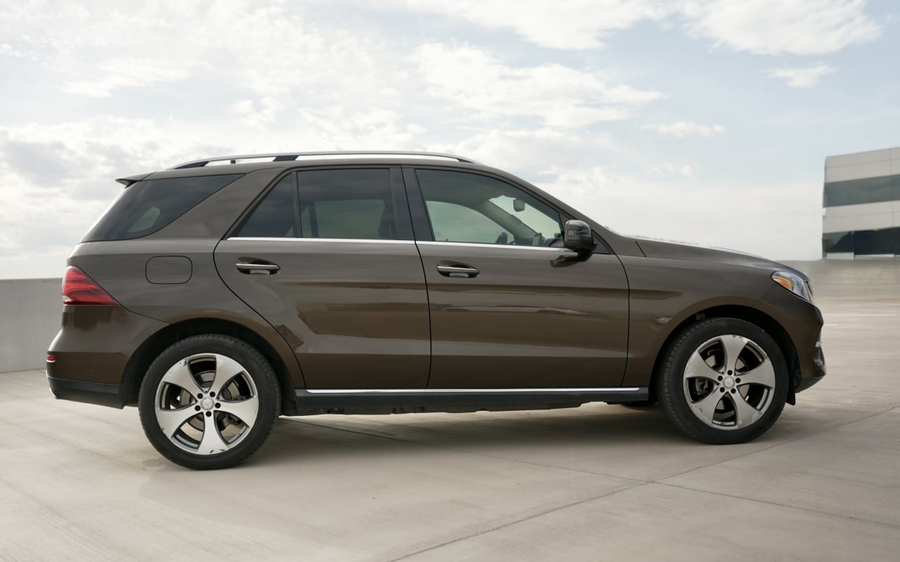 Side view of a brown SUV parked on a concrete lot
