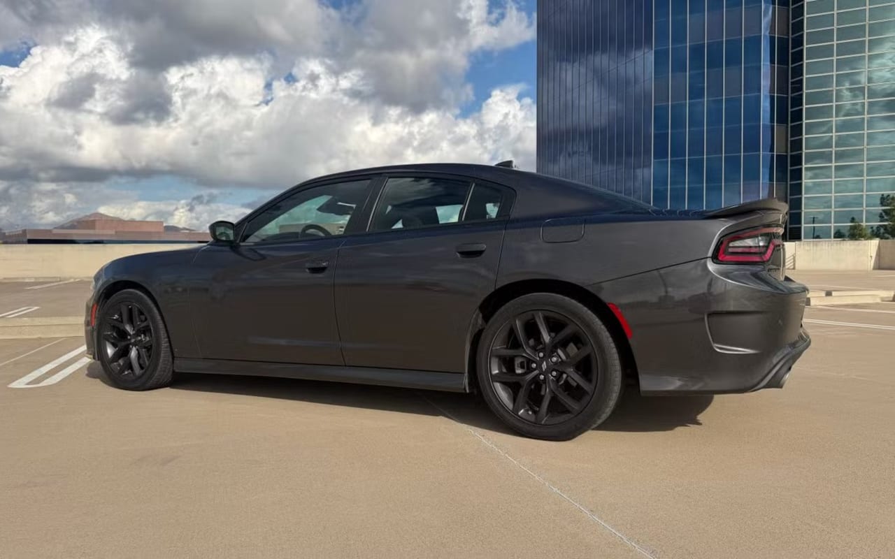 A dark gray Dodge Charger sedan, side-rear view, parked outdoors
