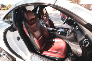 Red leather interior of a white convertible car with open door