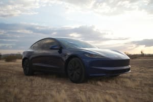 A striking blue Tesla electric car in a desert landscape under a cloudy sunset sky