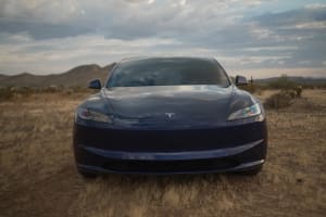 Front view of a blue Tesla electric car parked in a desert landscape, ready for your next car rental journey