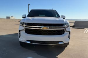 Front view of a white Chevrolet SUV in a sunny parking lot, ideal for car rental journeys