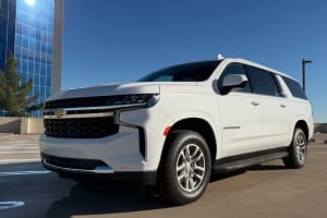 Bright white Chevrolet Suburban SUV parked on a sunny outdoor lot, excellent for car rental