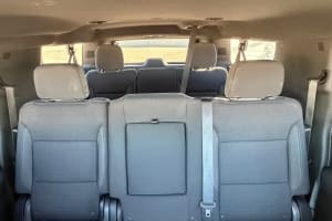 Spacious rear interior of an RV rental, featuring two rows of grey cloth seating with seatbelts, ready for passengers