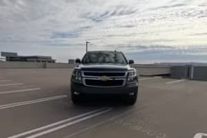 Front view of a dark SUV parked on a concrete deck under a cloudy sky