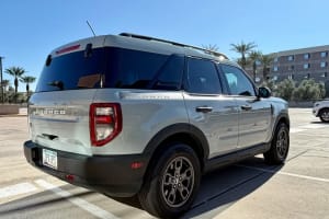 This light grey Ford Bronco Sport SUV, likely a car rental, is parked outdoors on a sunny day, rear-right view