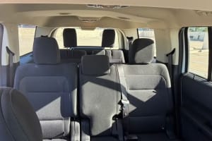 RV rental: Interior cabin with multiple rows of dark gray fabric seats, set for group travel