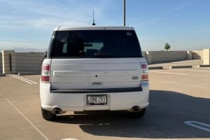 Rear of a white Ford Flex SUV, Arizona plate RMA 293, parked at an airport