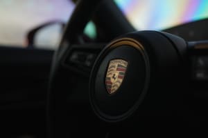 Experience luxury with a Porsche steering wheel and emblem, available for your next premium car rental adventure