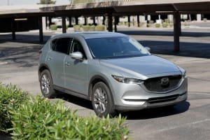 Silver Mazda CX-5 SUV, a versatile travel option, parked under a shade structure