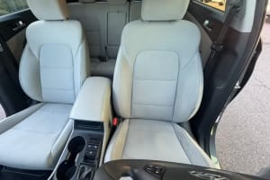 Clean car rental interior with light gray fabric front seats, center console with cupholders, and rear seats