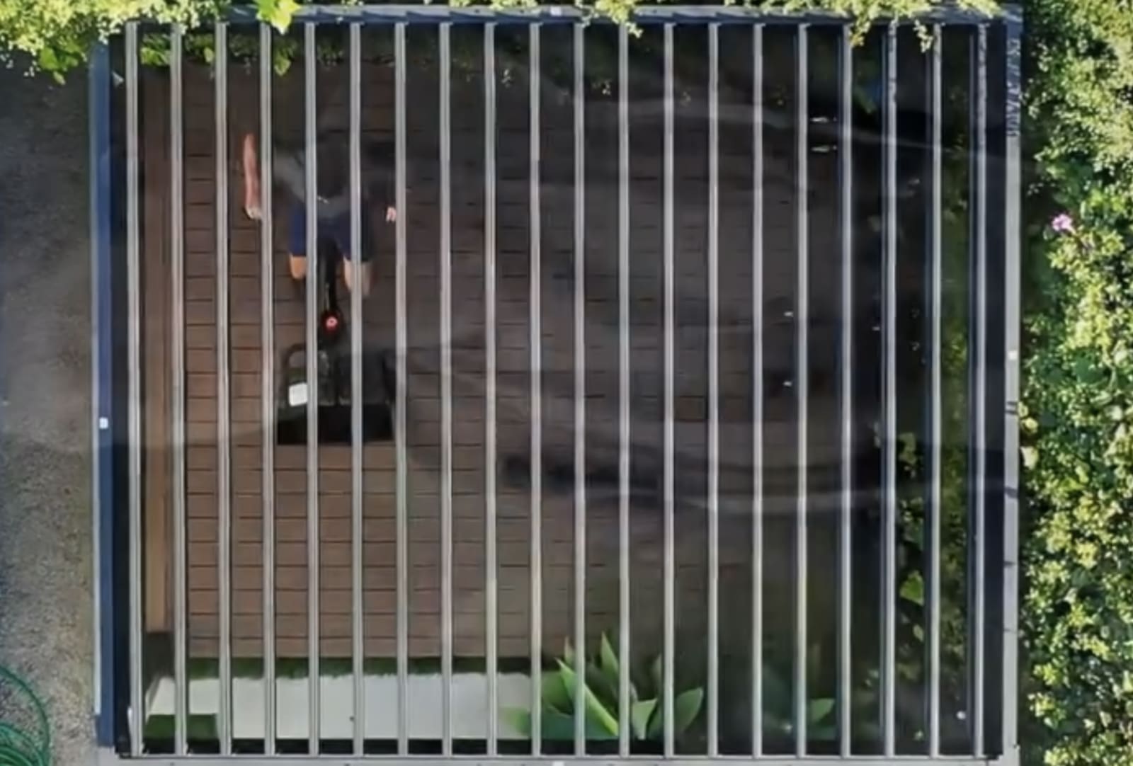 Overhead view of an aluminum pavilion frame and adjustable louvers surrounded by greenery