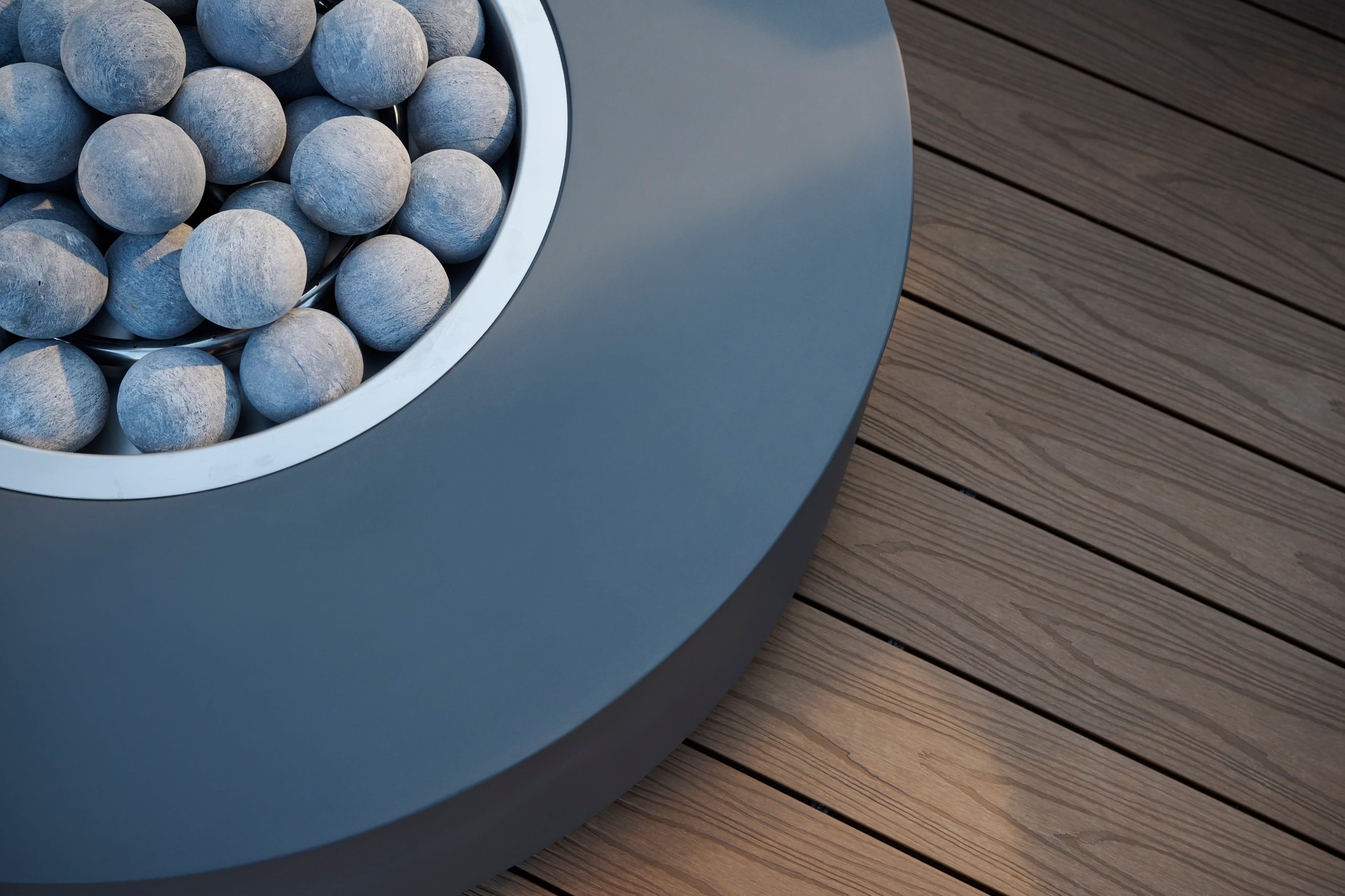Fire bowl filled with lava spheres resting on warm composite decking